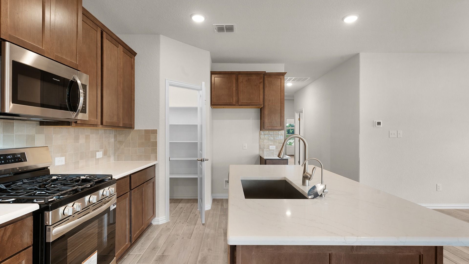en includes gas cooking, spacious corner pantry, and ample cabinet space for storage and everyday convenience.