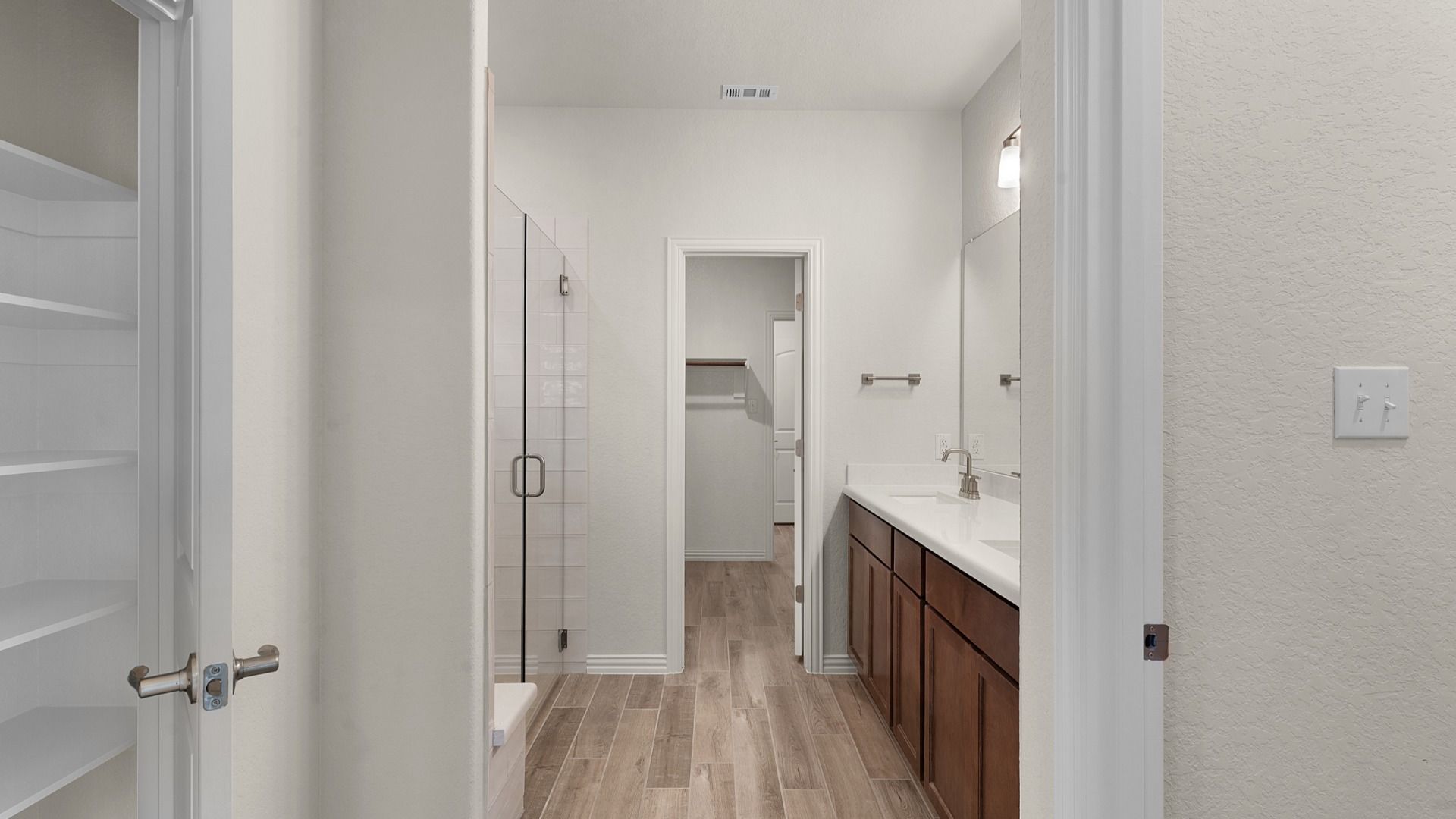 Dual vanity, frameless glass shower with white ceramic tile, and a window for bright, spa-like comfort.