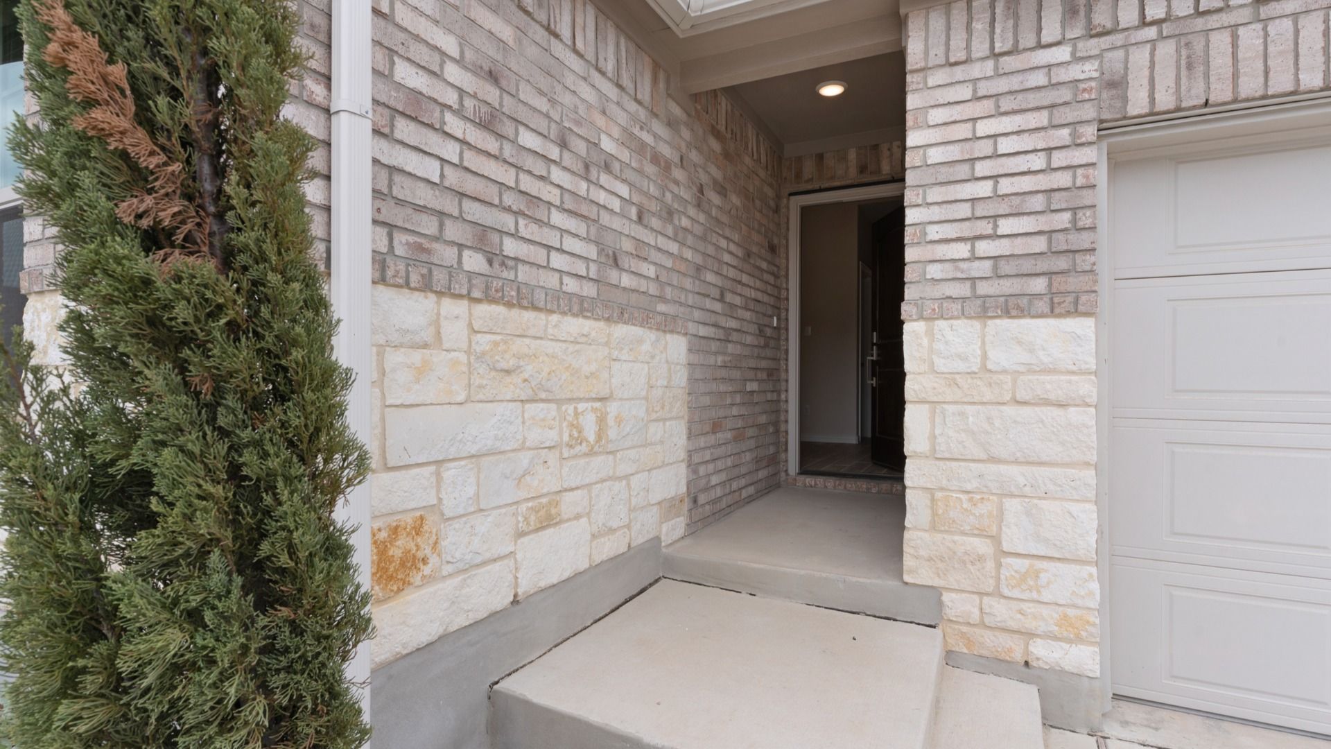 Brick and stone inviting home complete with lush landscaping and a detailed metal roof accent.