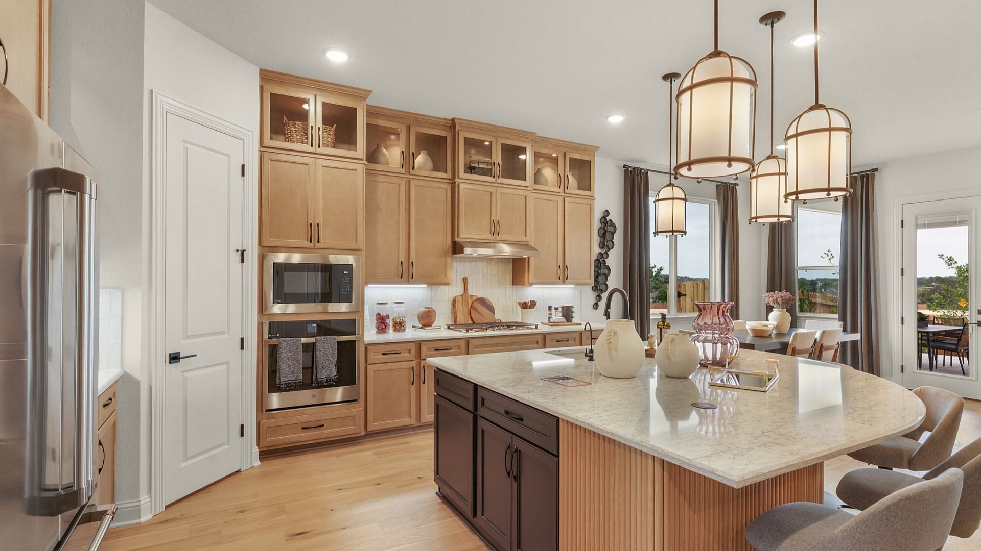 Modern kitchen with ceiling-height cabinets, built-in appliances, statement lighting, and a large center island.