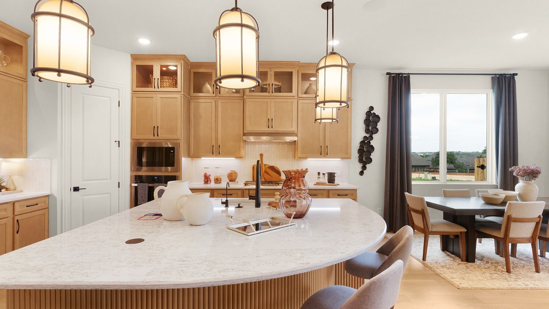 Modern kitchen with ceiling-height cabinets, built-in appliances, statement lighting, and a large center island.