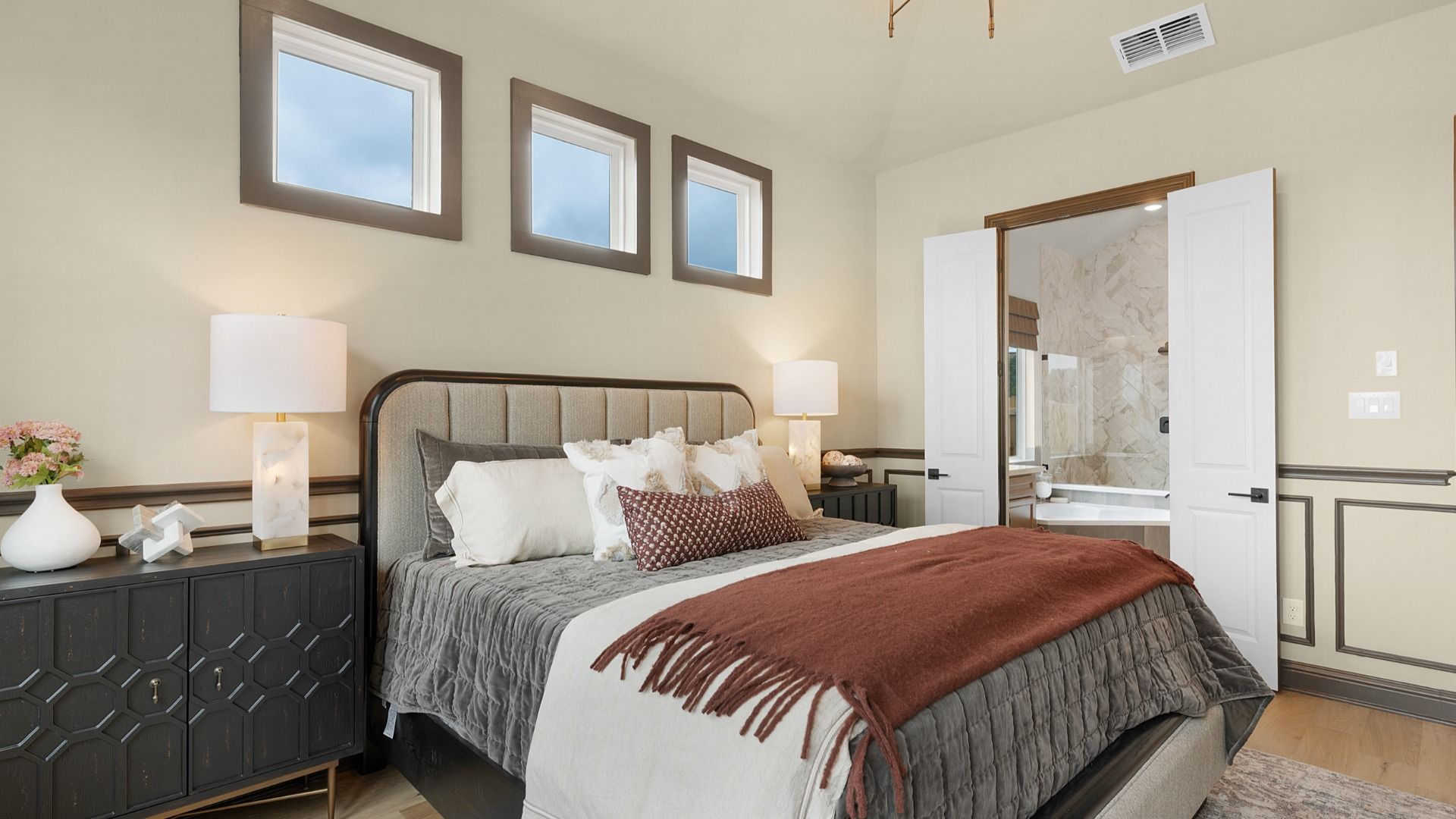 Owner’s suite with abundant natural light, woodwork details, and warm-toned flooring for a refined feel.