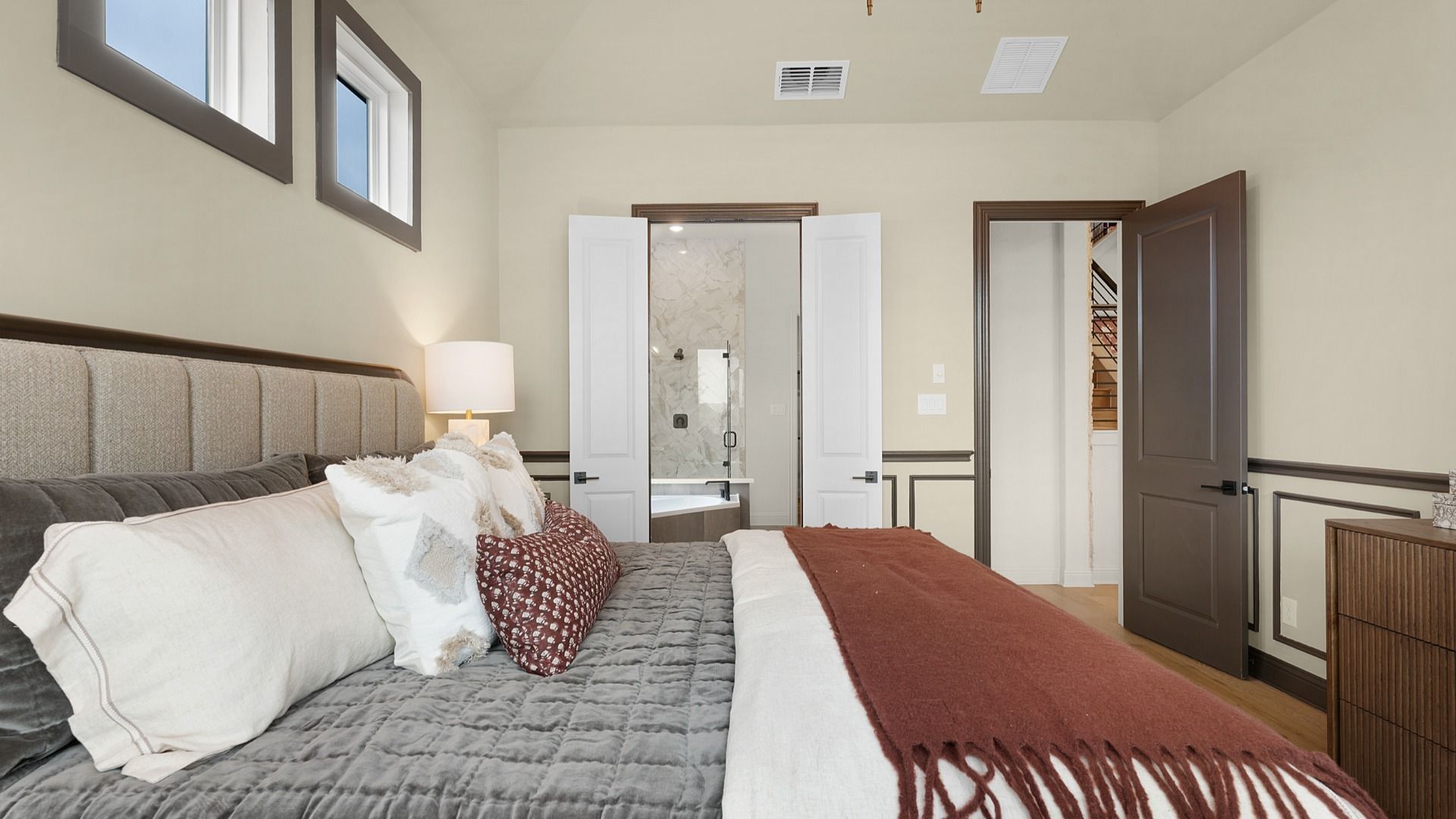 Owner’s suite with abundant natural light, woodwork details, and warm-toned flooring for a refined feel.