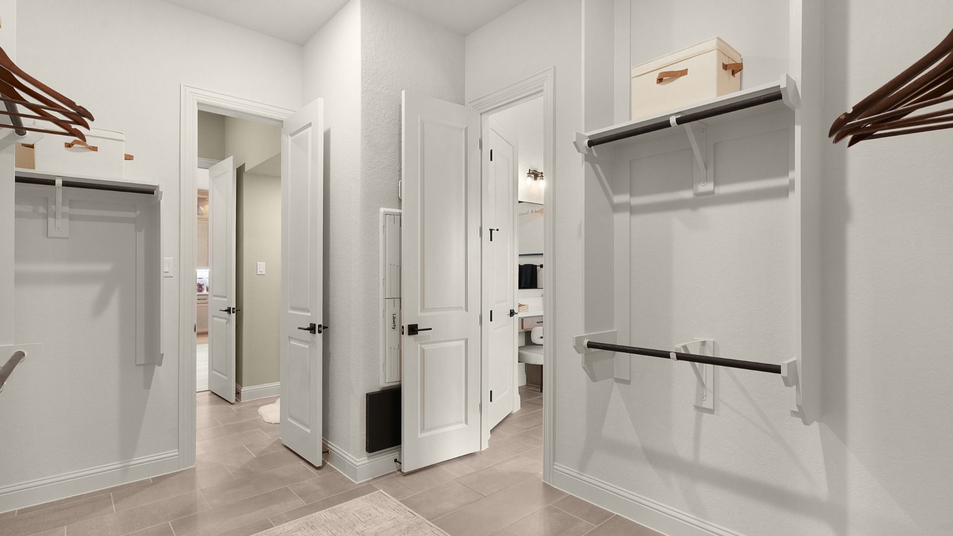 Spacious owner’s closet with wooden hanging rods and direct access to the laundry room for convenience.
