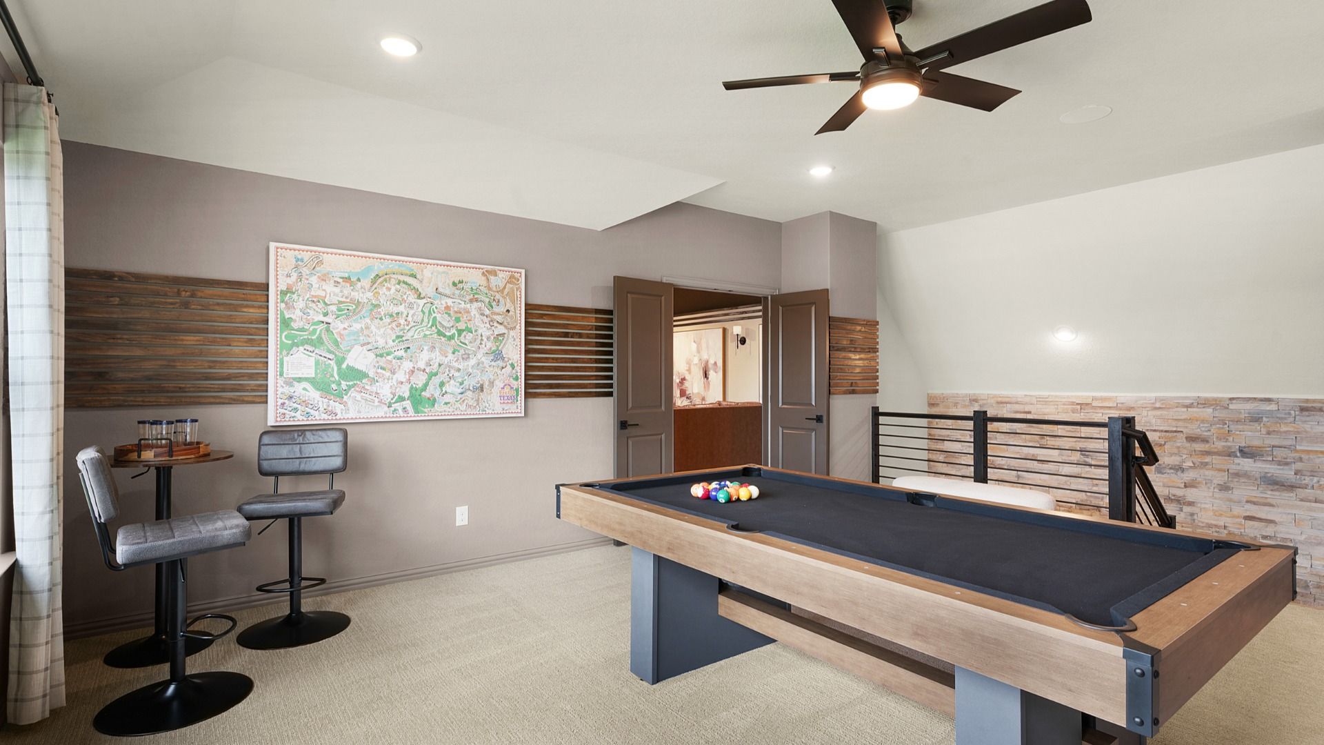 Second-floor game room with large windows and a ceiling fan, connected to a dedicated media room for entertainment.