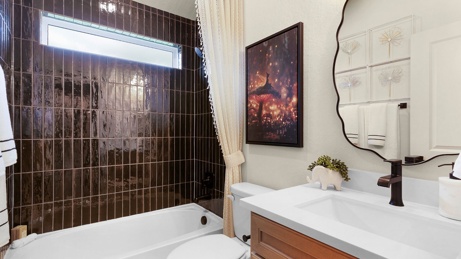 Secondary bath features a sleek tile finish, modern vanity, and a window at the shower/bath for natural light.