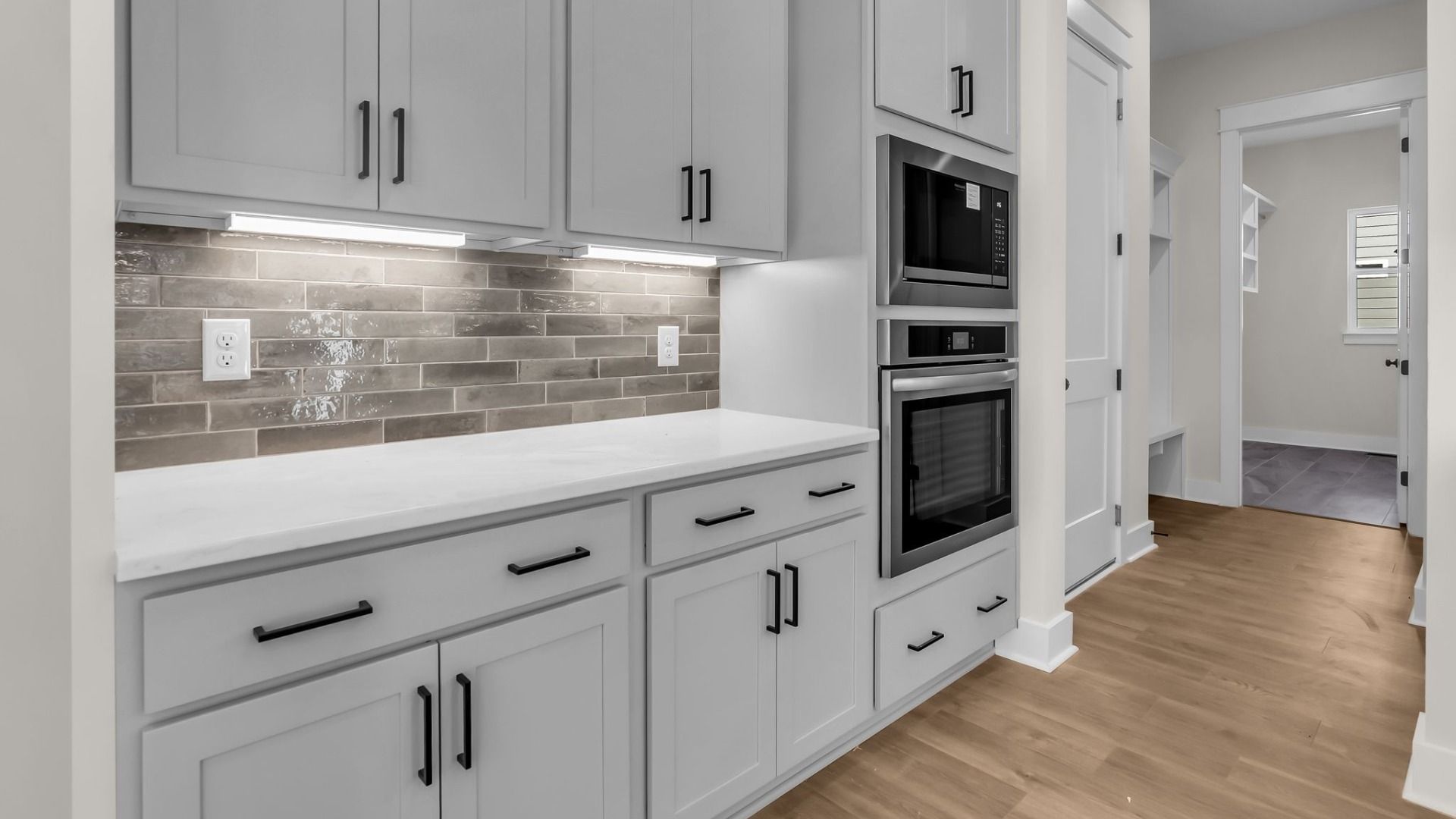 Kitchen with spacious grey cabinetry, sleek tile backsplash, and light quartz countertops