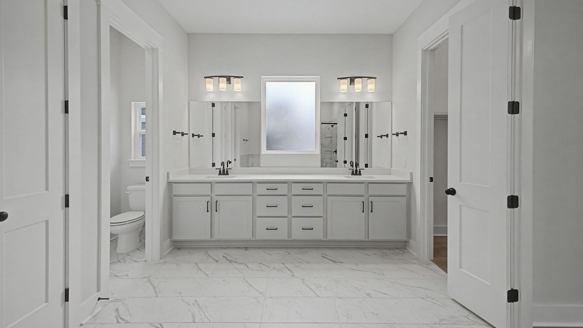 Bathroom with luxury dual vanity, blurred window, and designated area for toilet