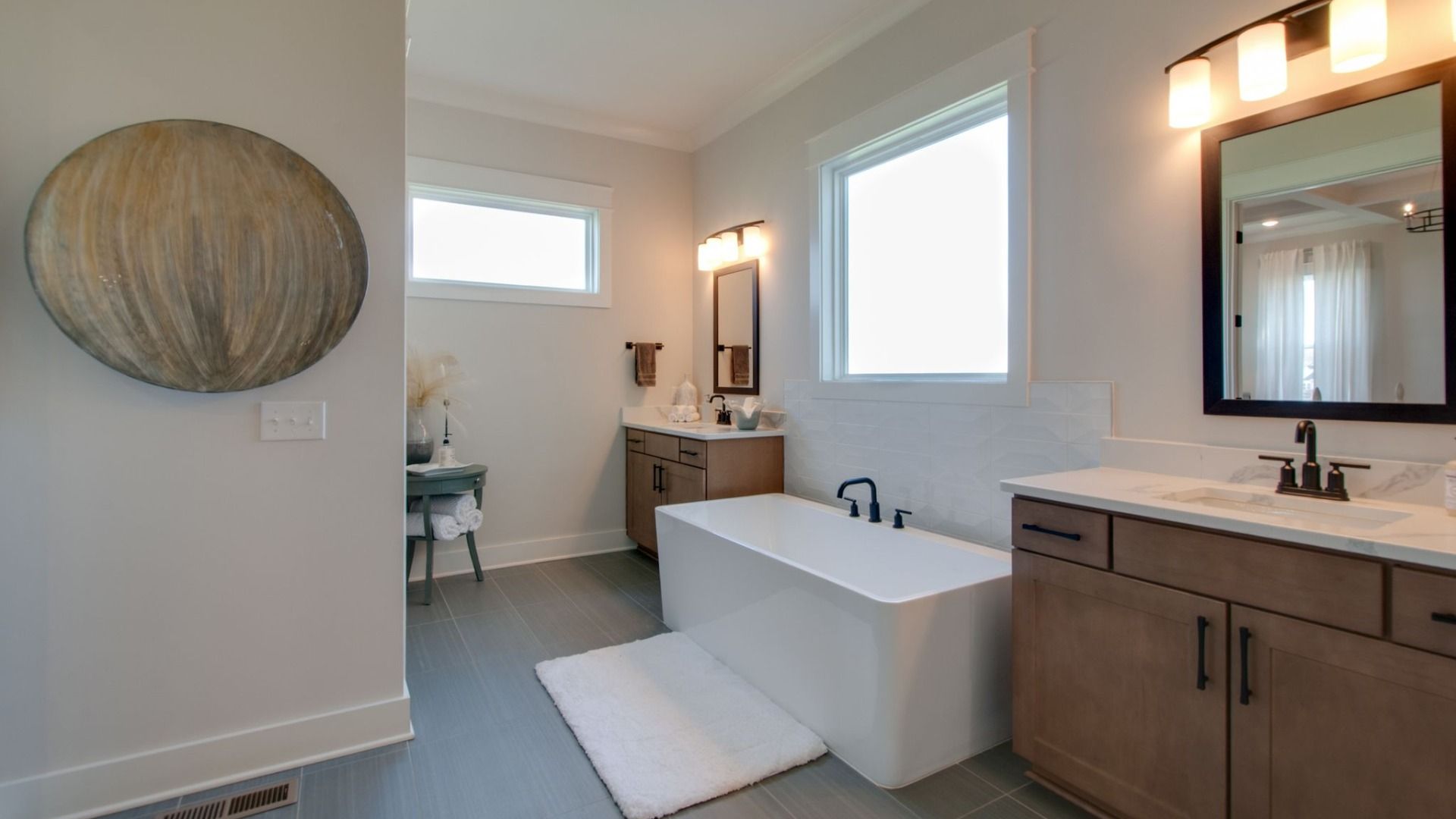 Bathroom with double vanity, tub, and window