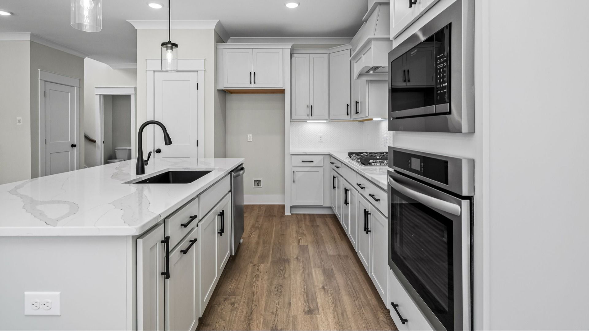 Kitchen with light cabinetry, quartz countertops, and tile backsplash