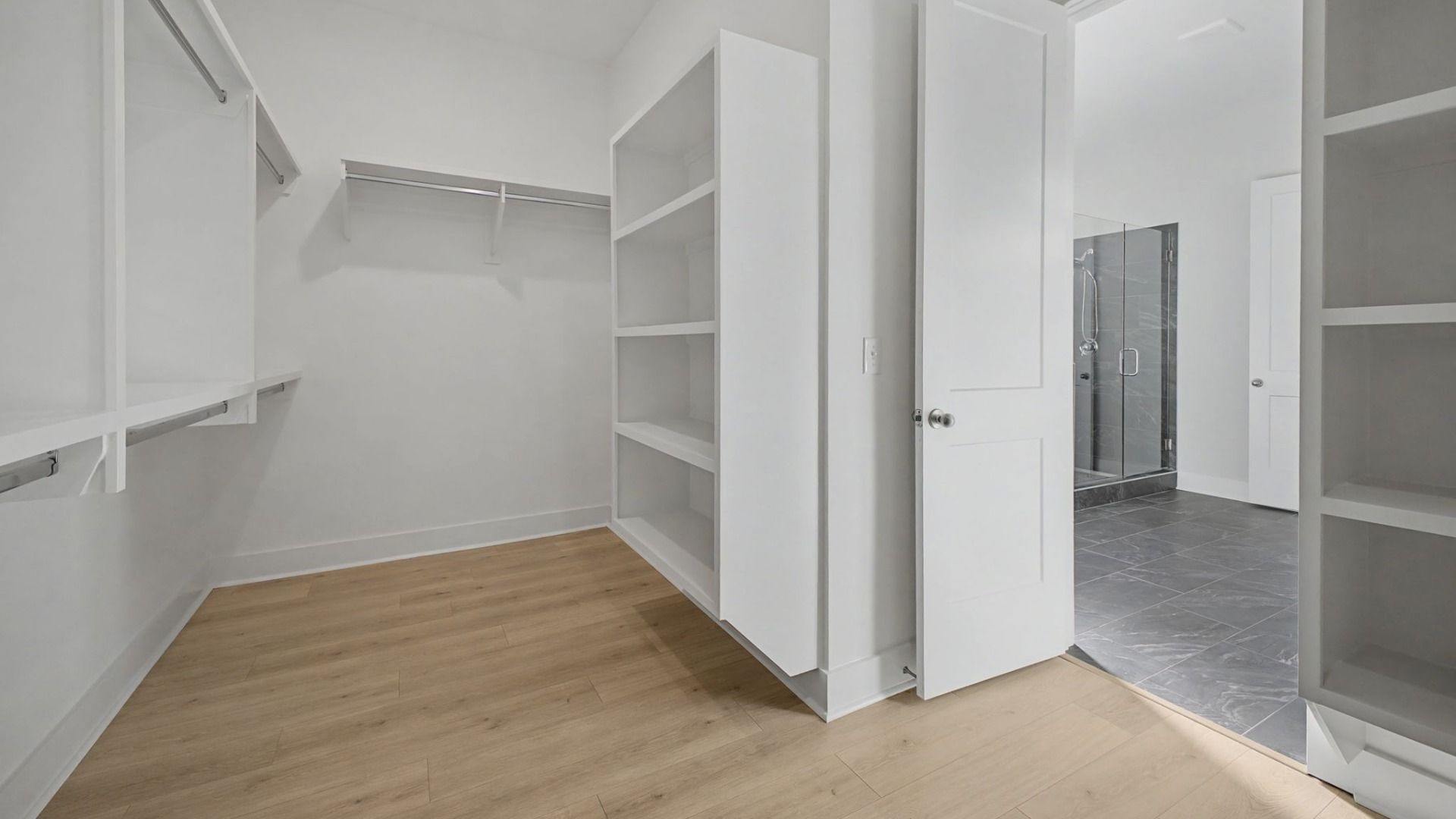 Spacious primary closet with built-in shelving with easy access to primary bathroom