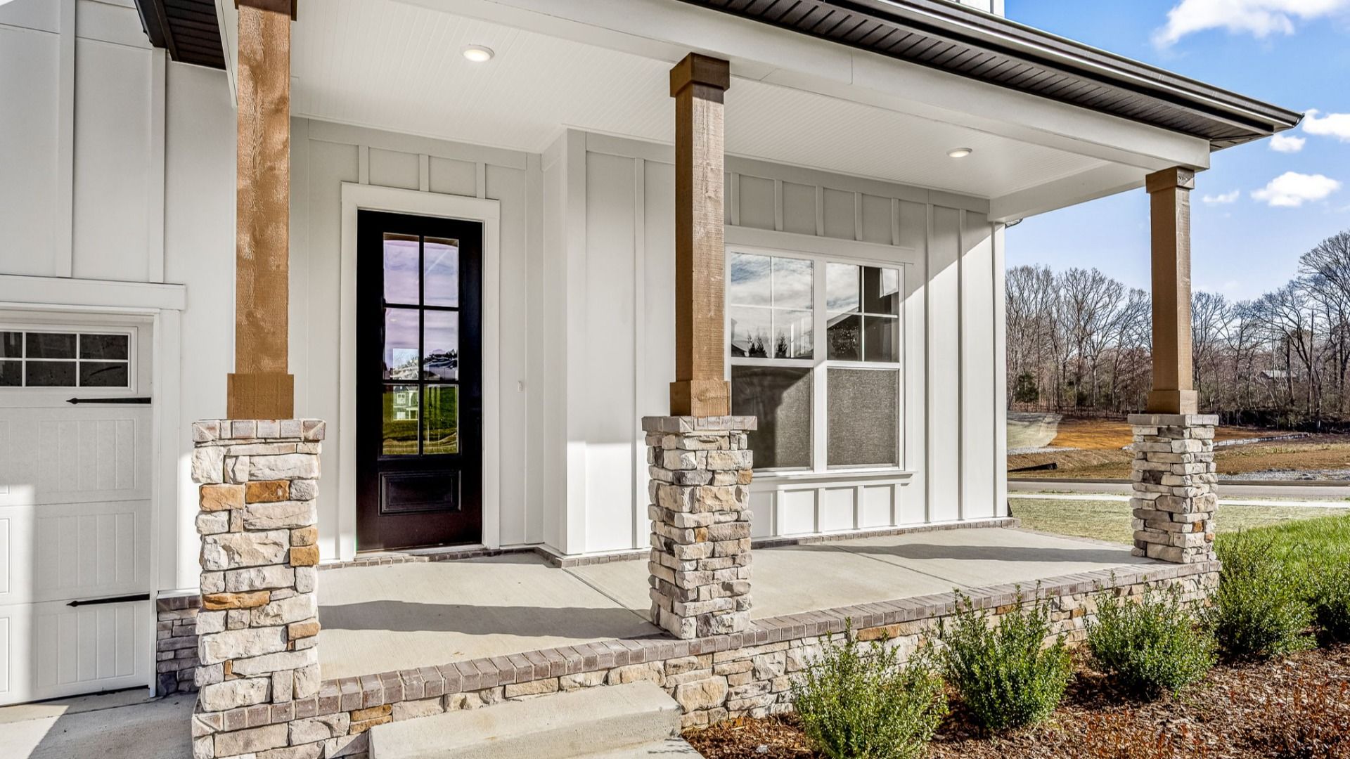 Luxurious front entryway into the home with black French door with brick accents