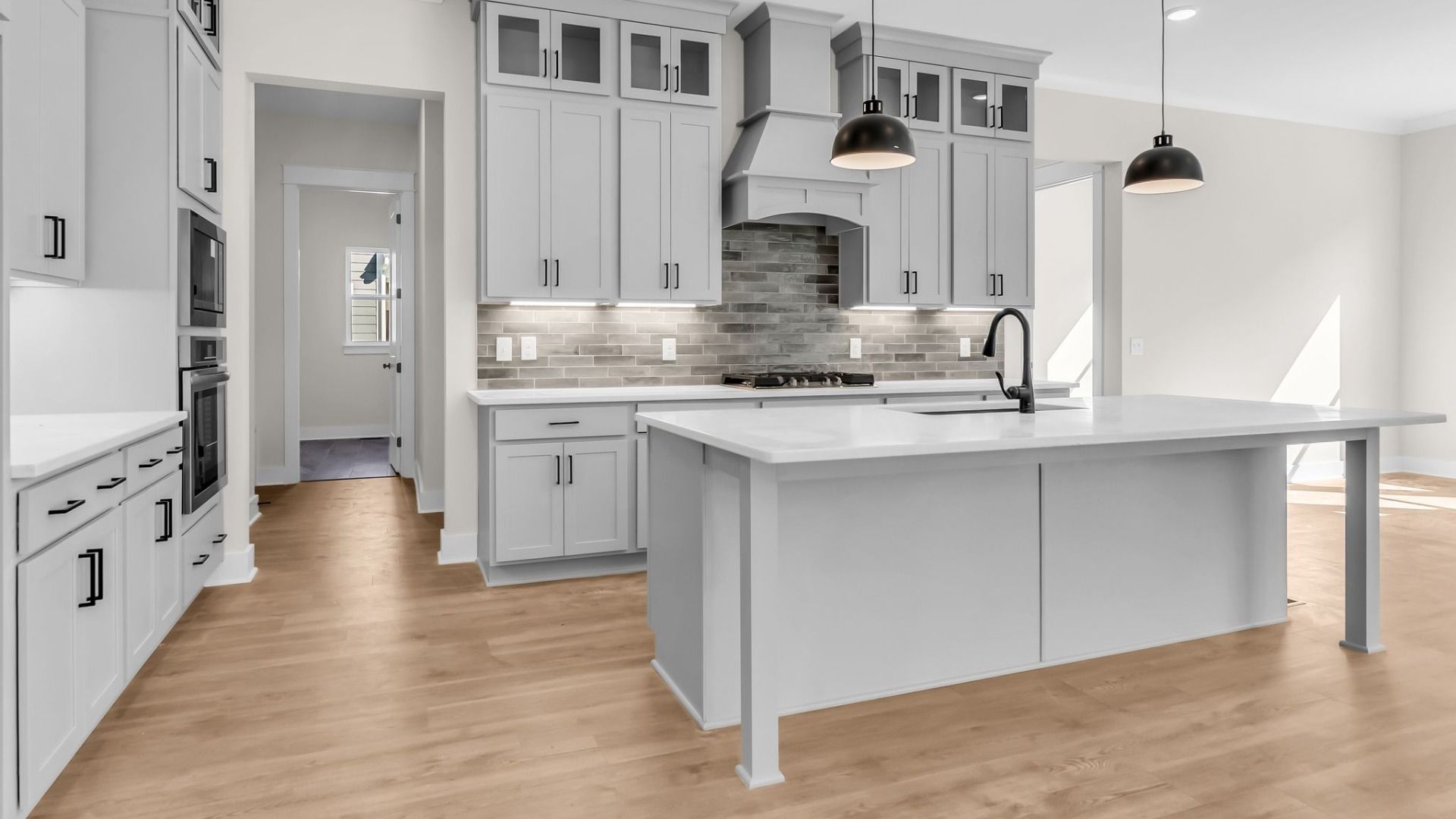 Kitchen with spacious light grey cabinetry, beautiful quartz countertops, and view into the dining area