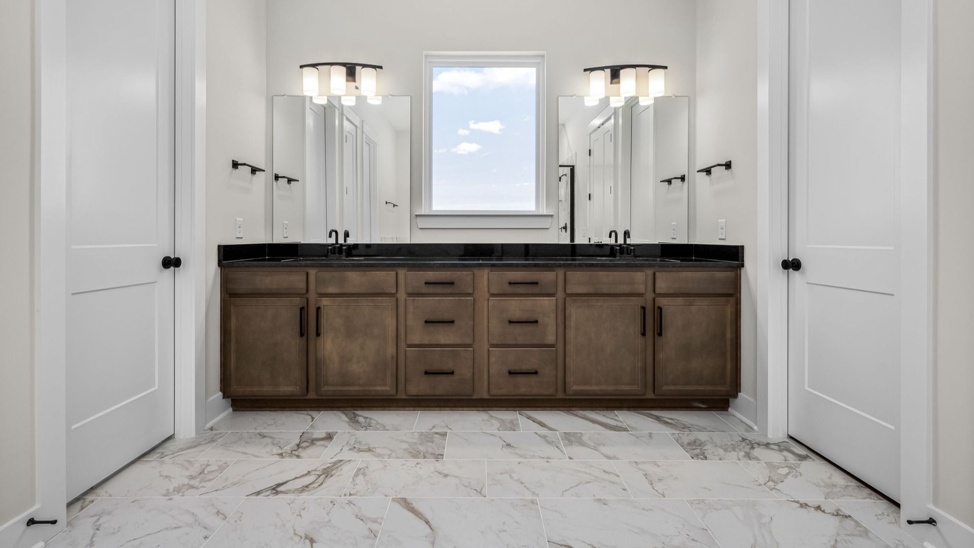 Luxurious bathroom with dark cabinetry, dual vanity, and a window