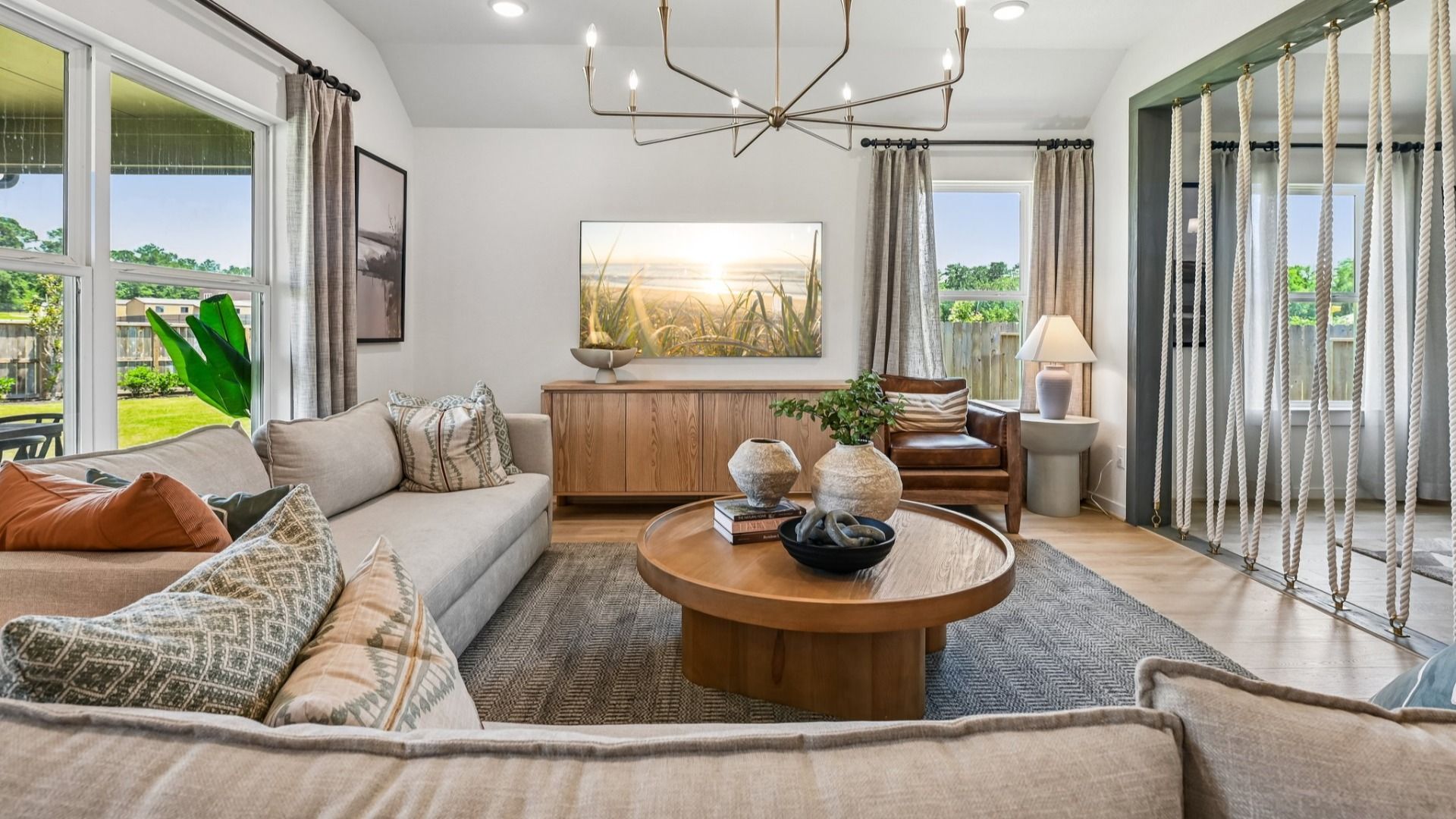 Luxurious Cielo living room features a striking chandelier and cozy seating, framing picturesque window views.