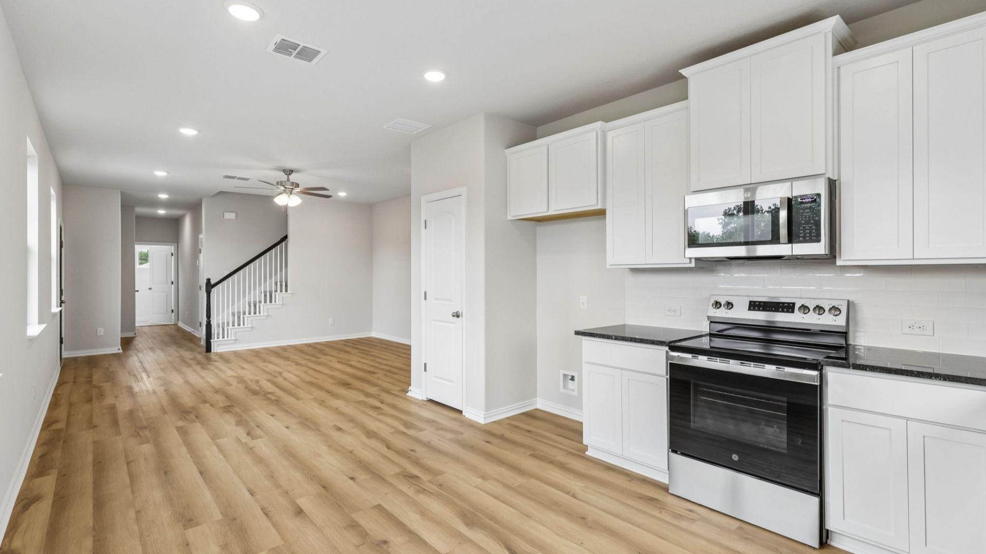 Kitchen is bright with 42 inch white cabinetry, sleek contrasting black countertops, and stainless steel appliances