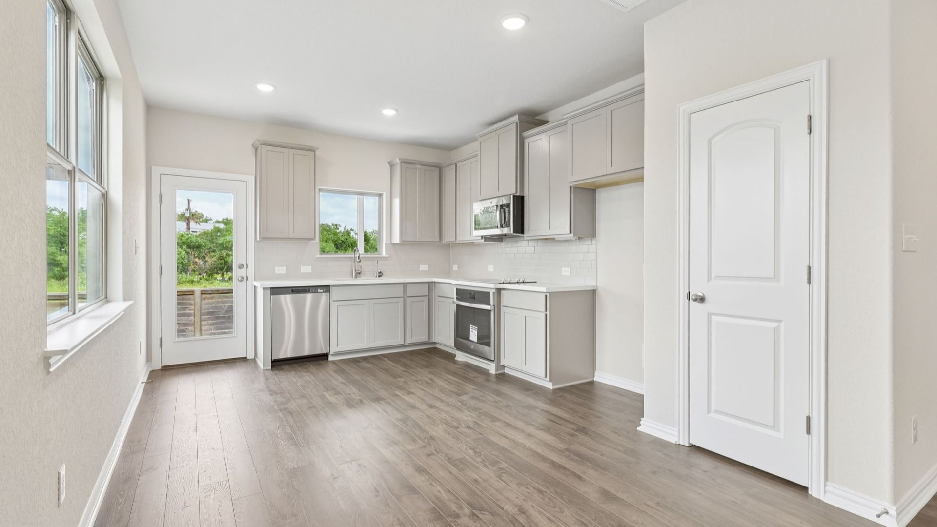 Kitchen is bright with 42 inch grey cabinetry, sleek complimentary white countertops, and stainless steel appliances