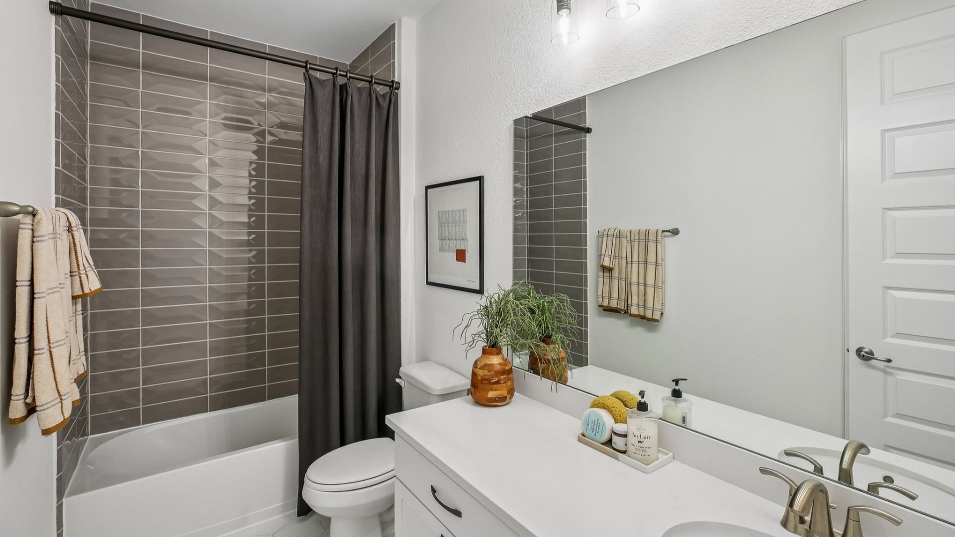 Luxurious bathroom features sleek white vanity, stylish gray tile, and premium fixtures in Cypress Green.