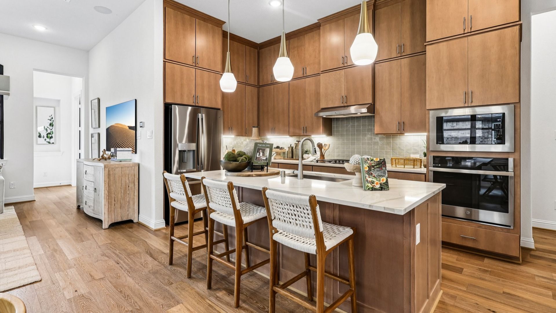 Elegant Sunterra kitchen boasts light wood cabinetry, sleek appliances, and a chic island centerpiece.