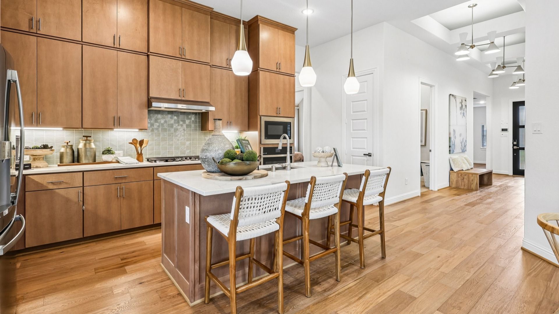 Experience luxury in Sunterra's kitchen featuring light wood cabinetry, sleek pendant lighting, and spacious island.