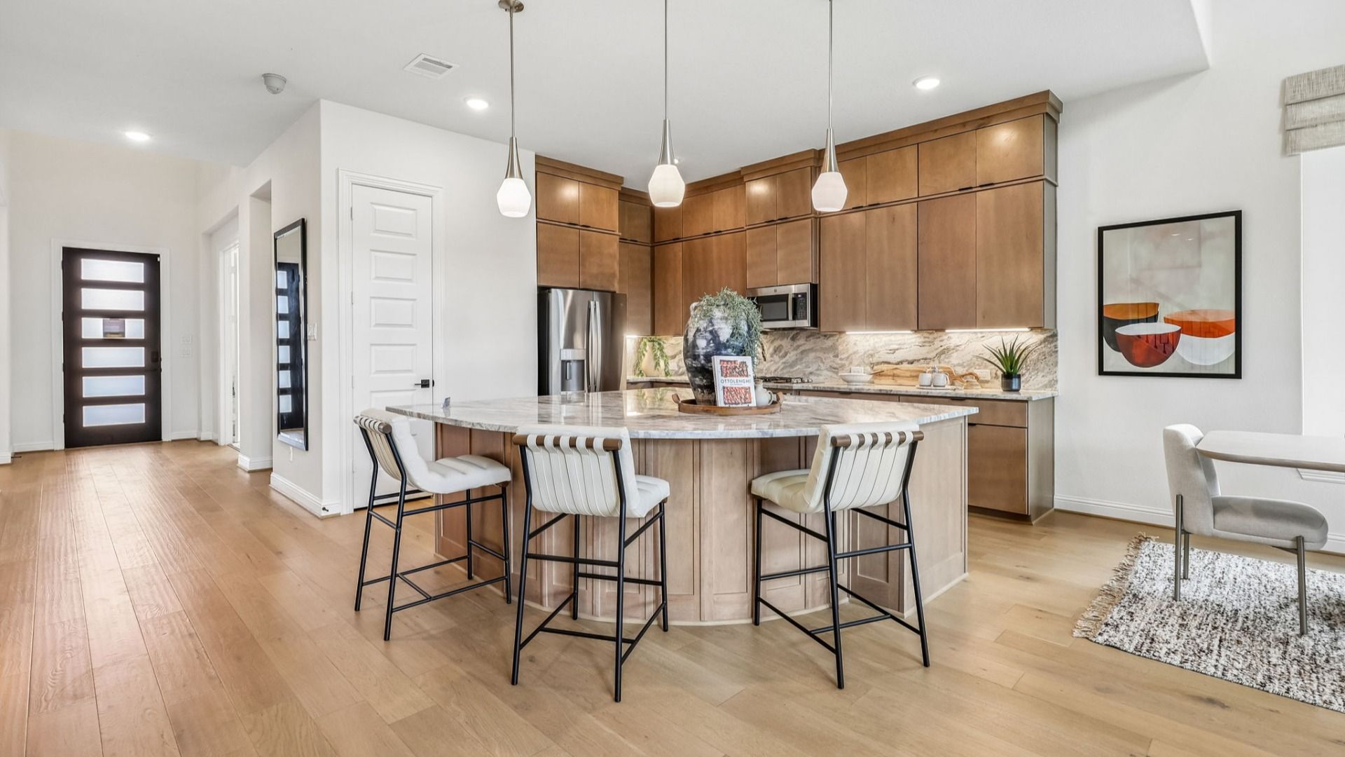 Luxurious Brookewater kitchen featuring marble countertops, custom wood cabinetry, and elegant pendant lighting.