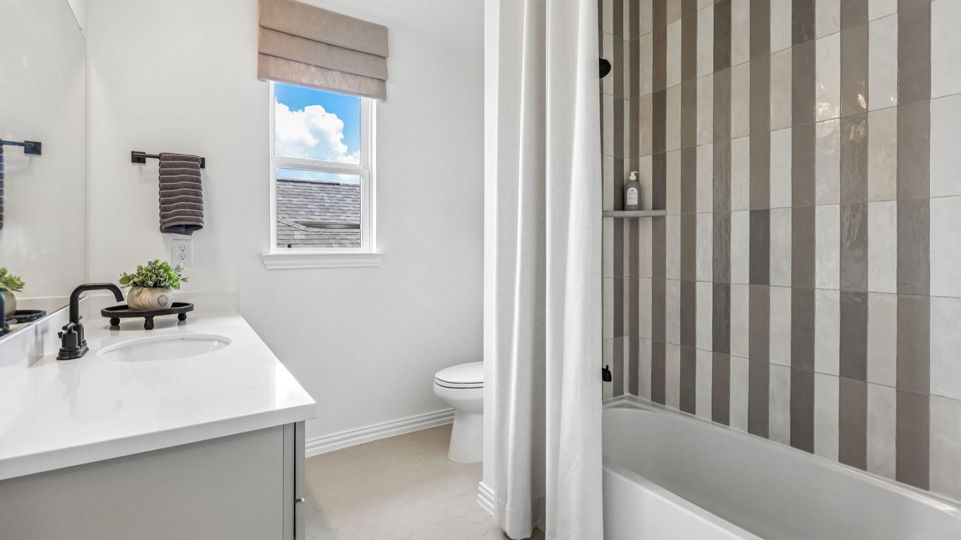 Luxurious Brookewater bathroom featuring sleek black fixtures and chic striped tiles, exuding modern elegance.