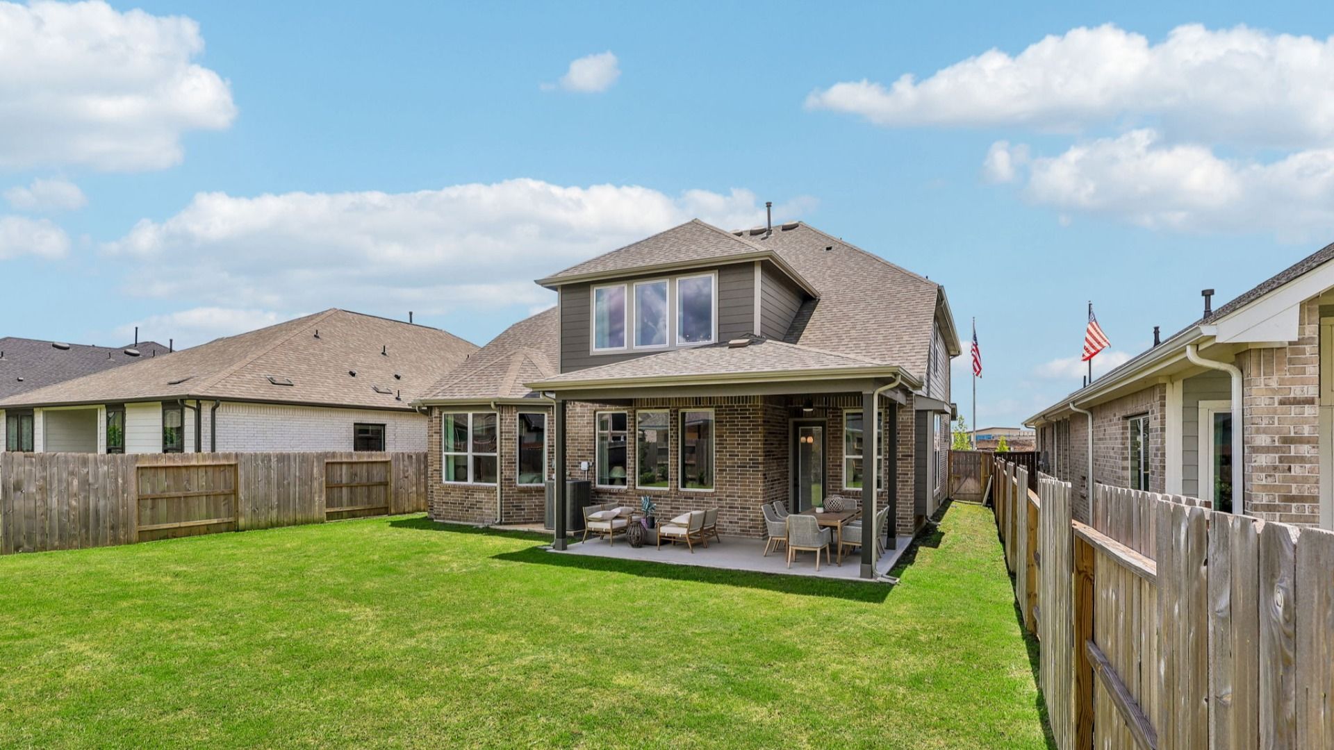 Elegant brick facade and covered patio highlight luxurious living in Brookewater community.