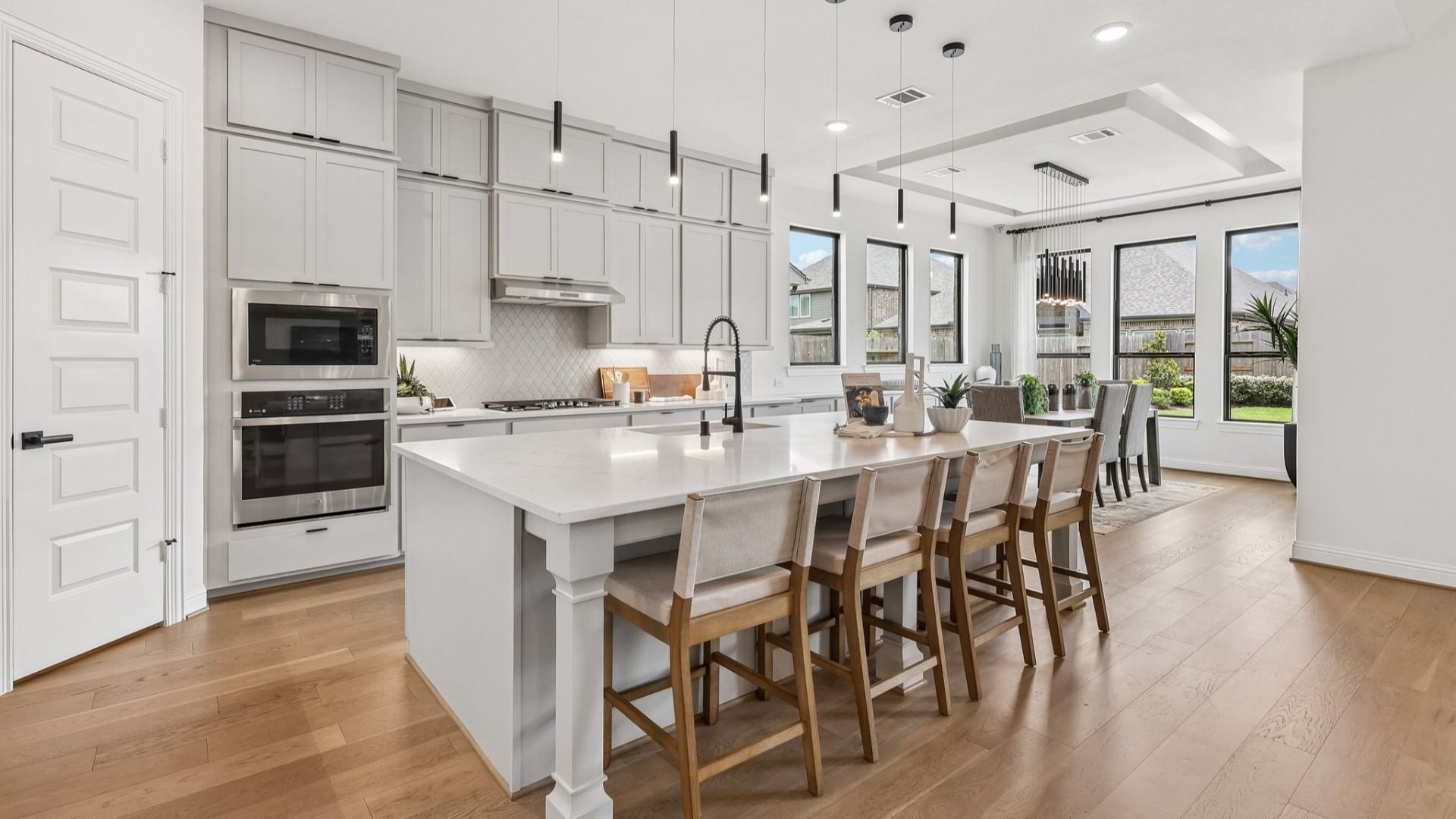 Luxurious kitchen features elegant white cabinetry, expansive island, and sleek pendant lighting in Brookewater.
