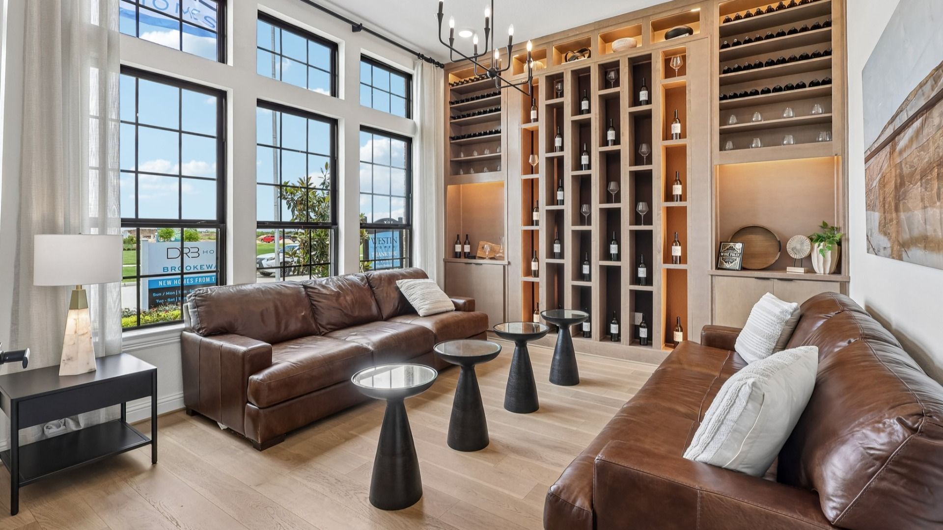 Elegant Brookewater living room features expansive windows, bespoke wine display, and refined leather furnishings.