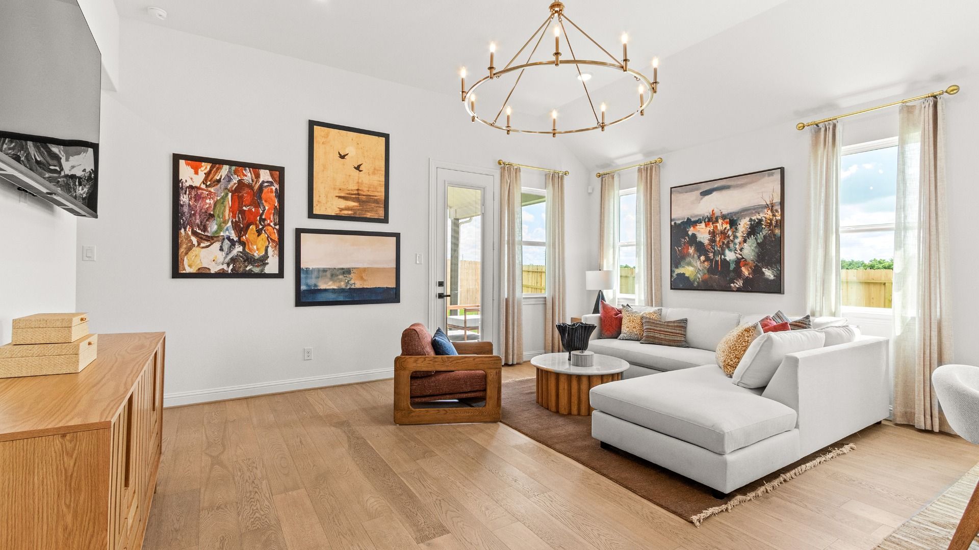 Bright living room featuring a modern gold chandelier and natural light from expansive windows.