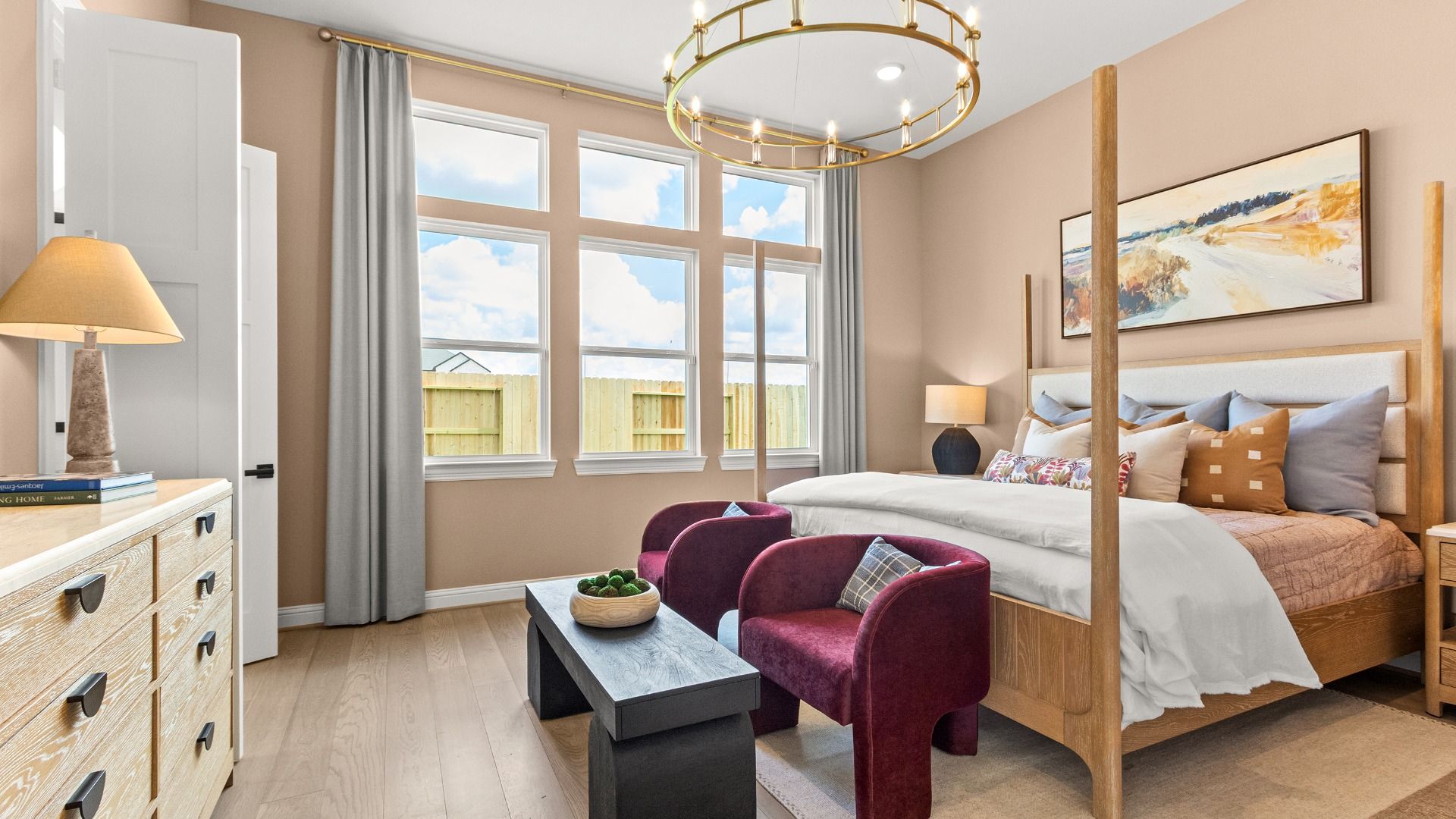 Large windows and a modern gold chandelier create a luxurious atmosphere in this beautifully crafted bedroom in Azalea.