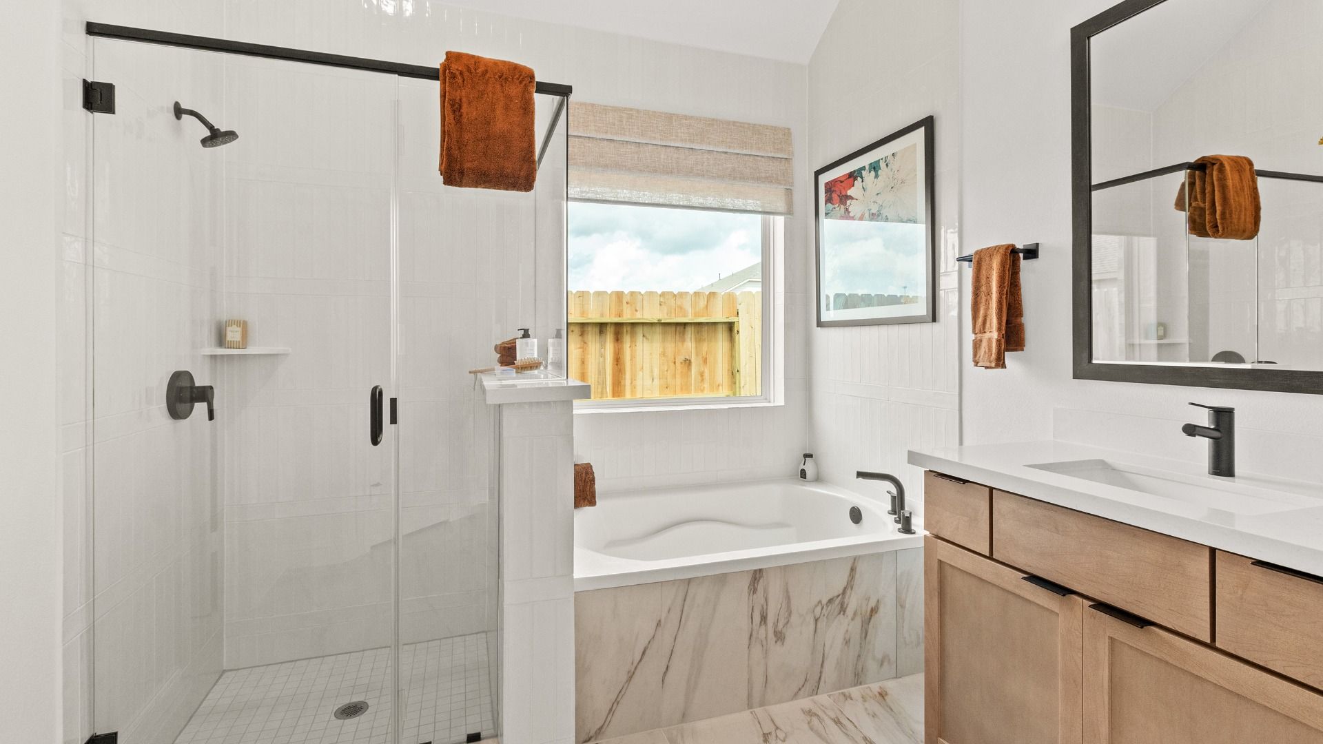 Sleek black fixtures, a walk-in shower, and soaking tub framed by natural light create a striking bathroom retreat in Azalea.