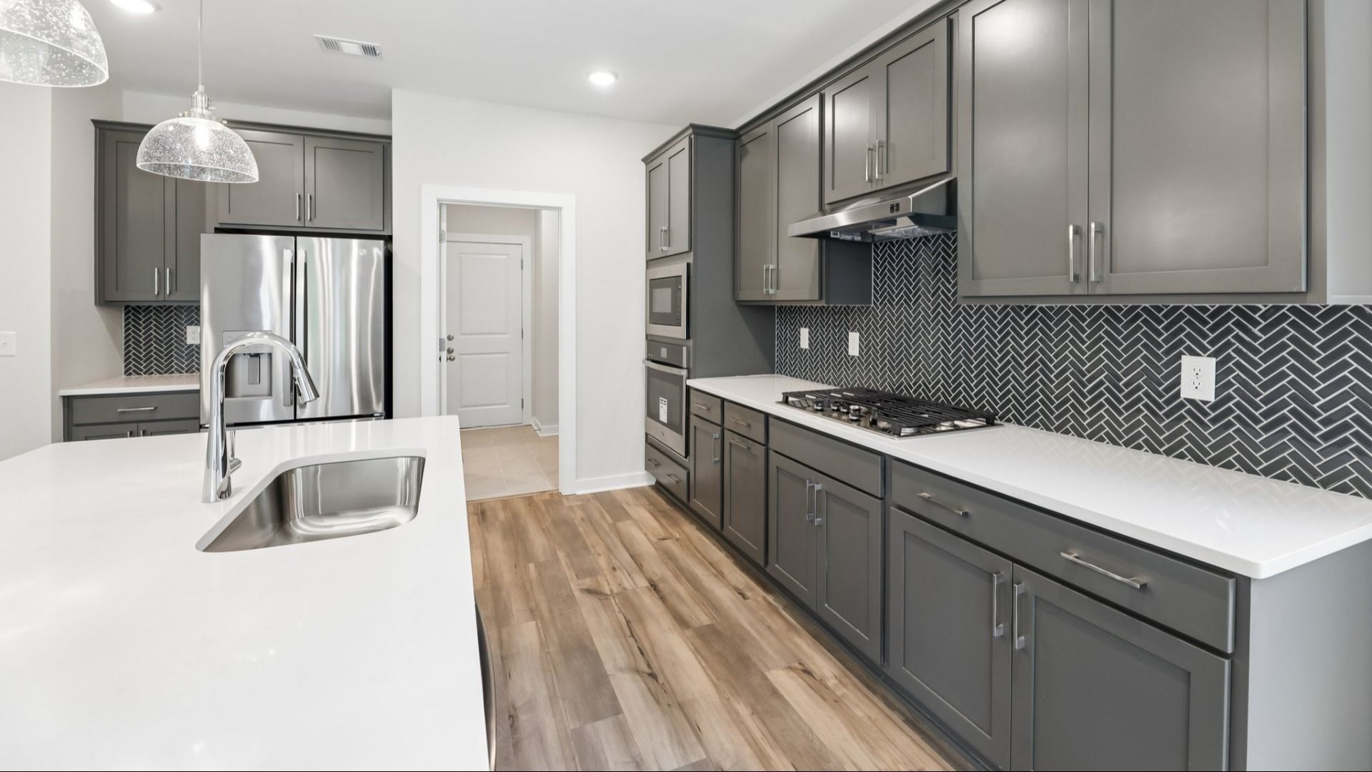 Kitchen with hard surface flooring, quartz countertops, and pendant lighting