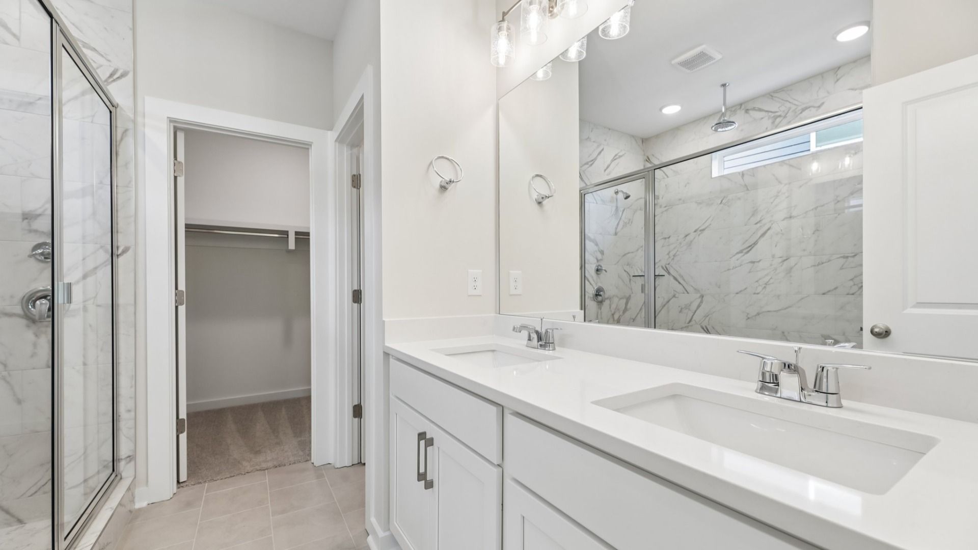 Primary bathroom with dual vanity and access to closet