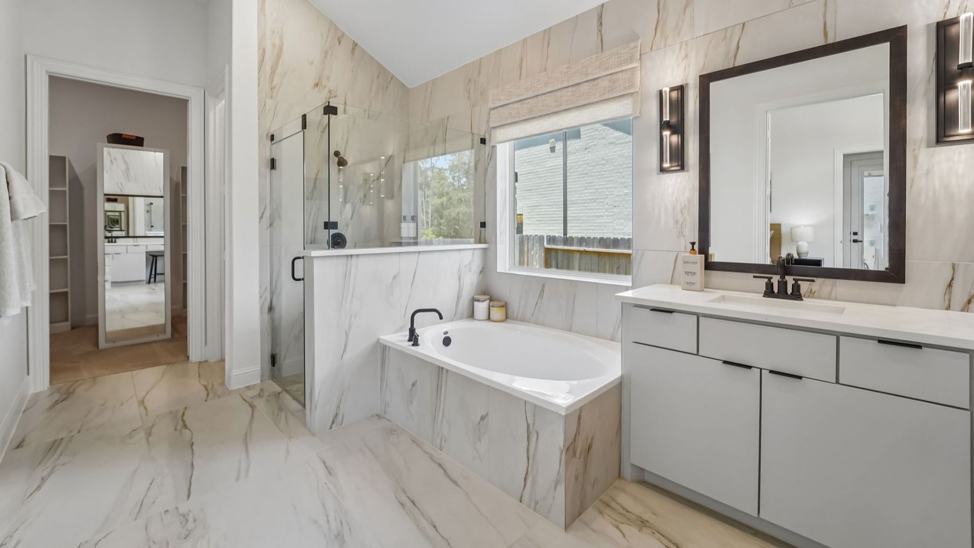 Sophisticated marble tiles grace this Woodlands Hills bathroom, boasting a sleek glass shower and sumptuous tub.
