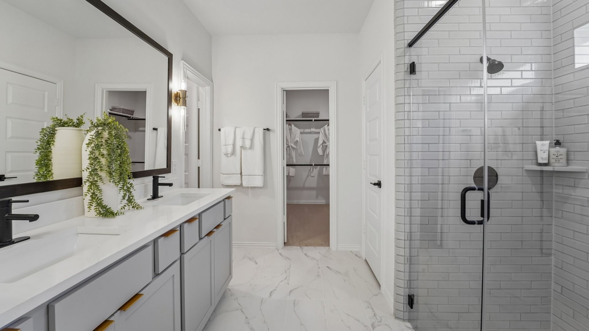 Marble tiles and frameless glass shower enhance this bathroom's elegance in The Woodlands Hills.
