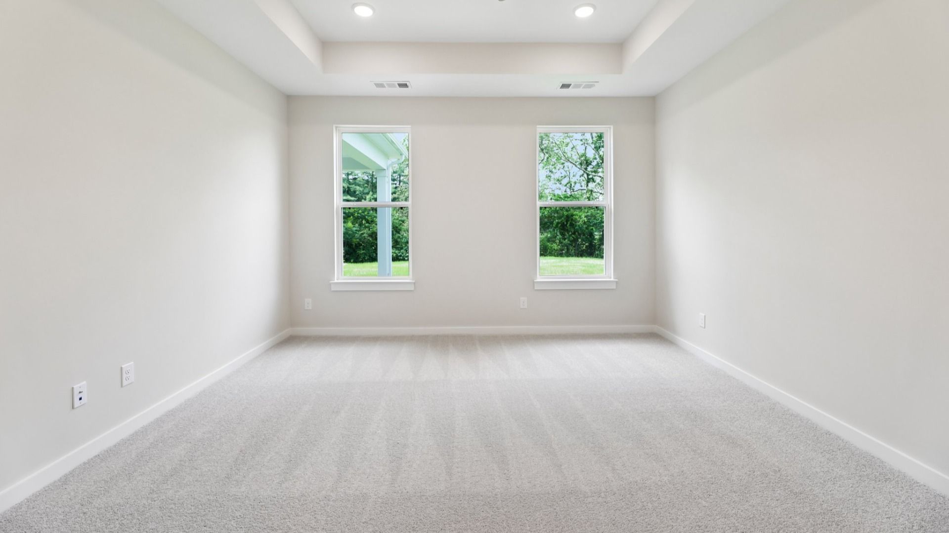 Primary Bedroom with tray ceiling and carpet