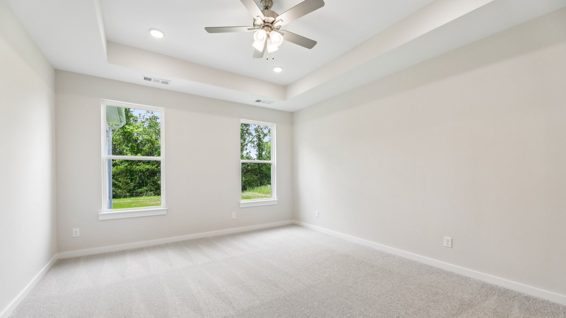 Primary Bedroom with tray ceiling, carpet, and ceiling fan