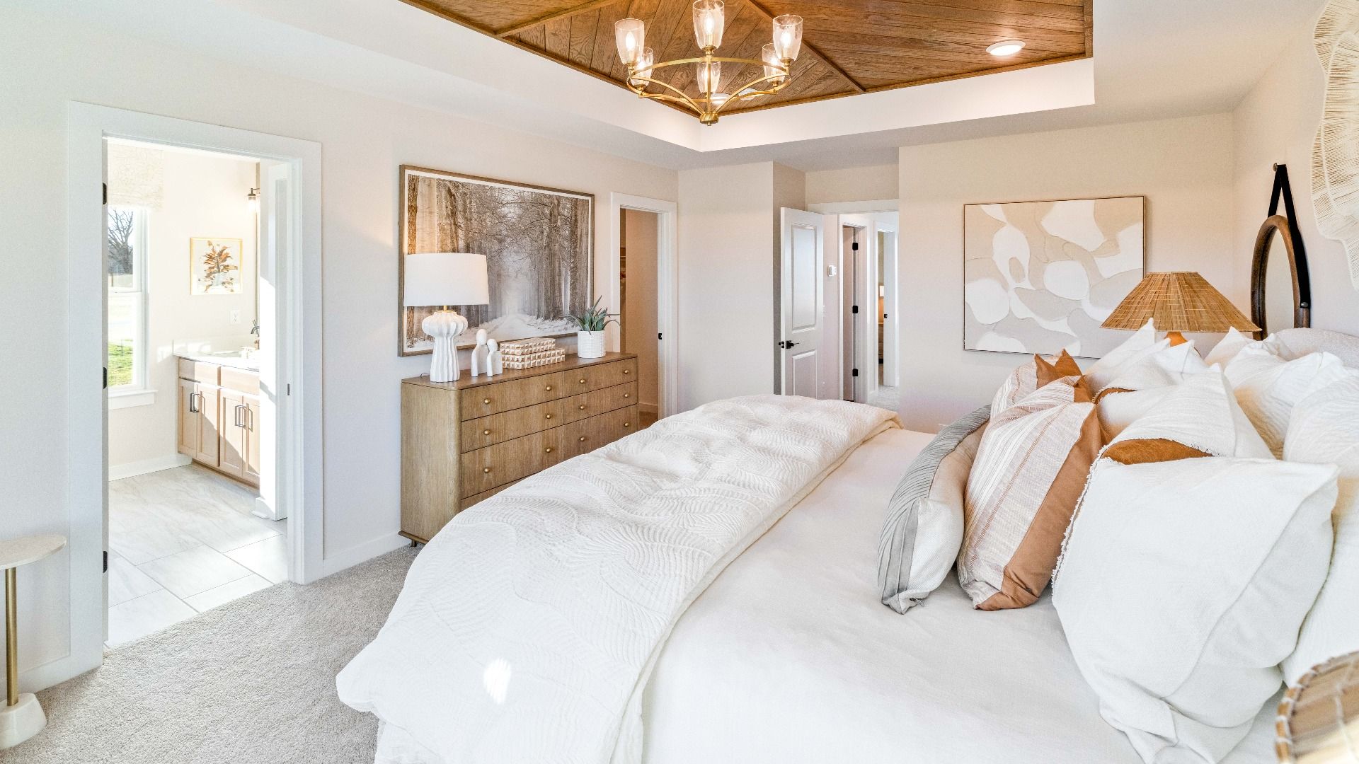 Primary bedroom with accent tray ceiling, windows, and carpet