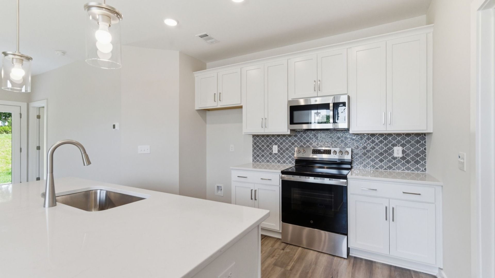 Kitchen with tile backsplash, pendant lighting, and quartz countertops