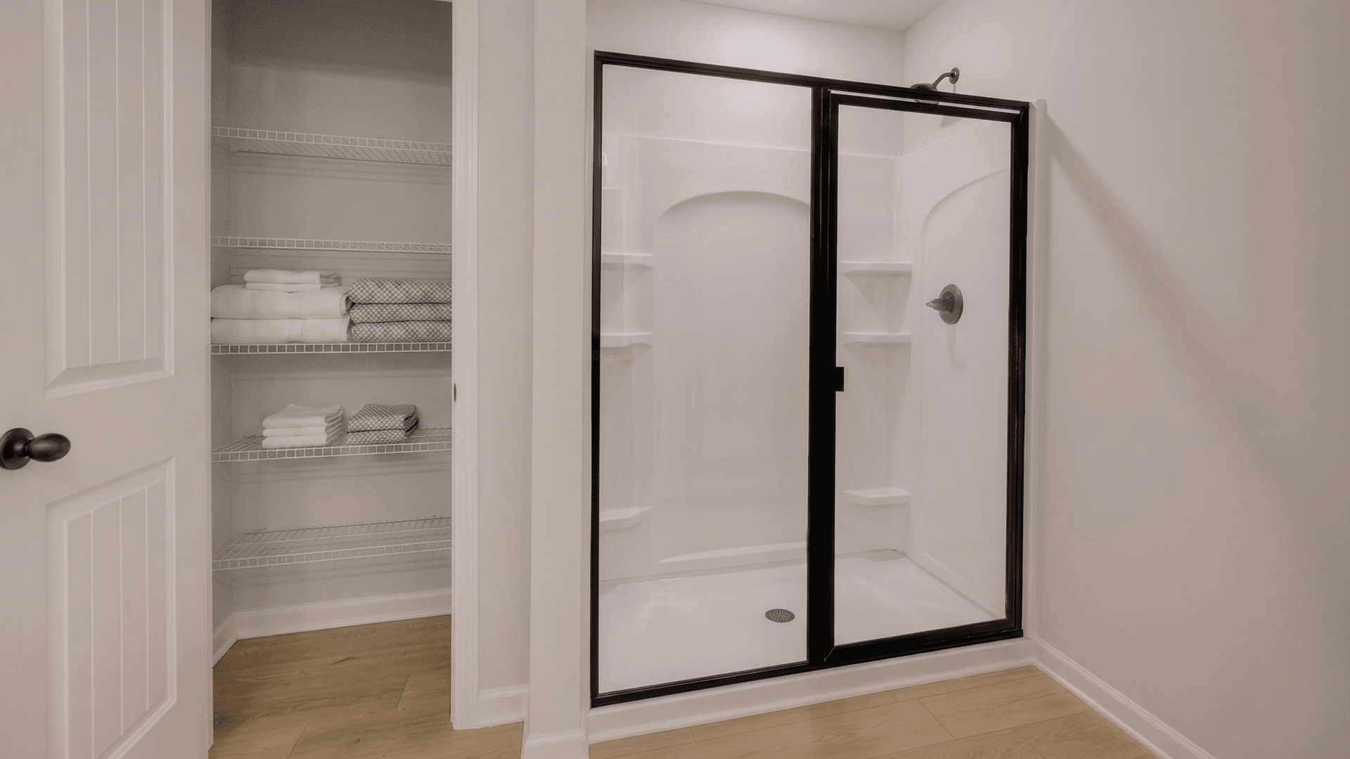 Primary bathroom with glass enclosed shower and linen closet