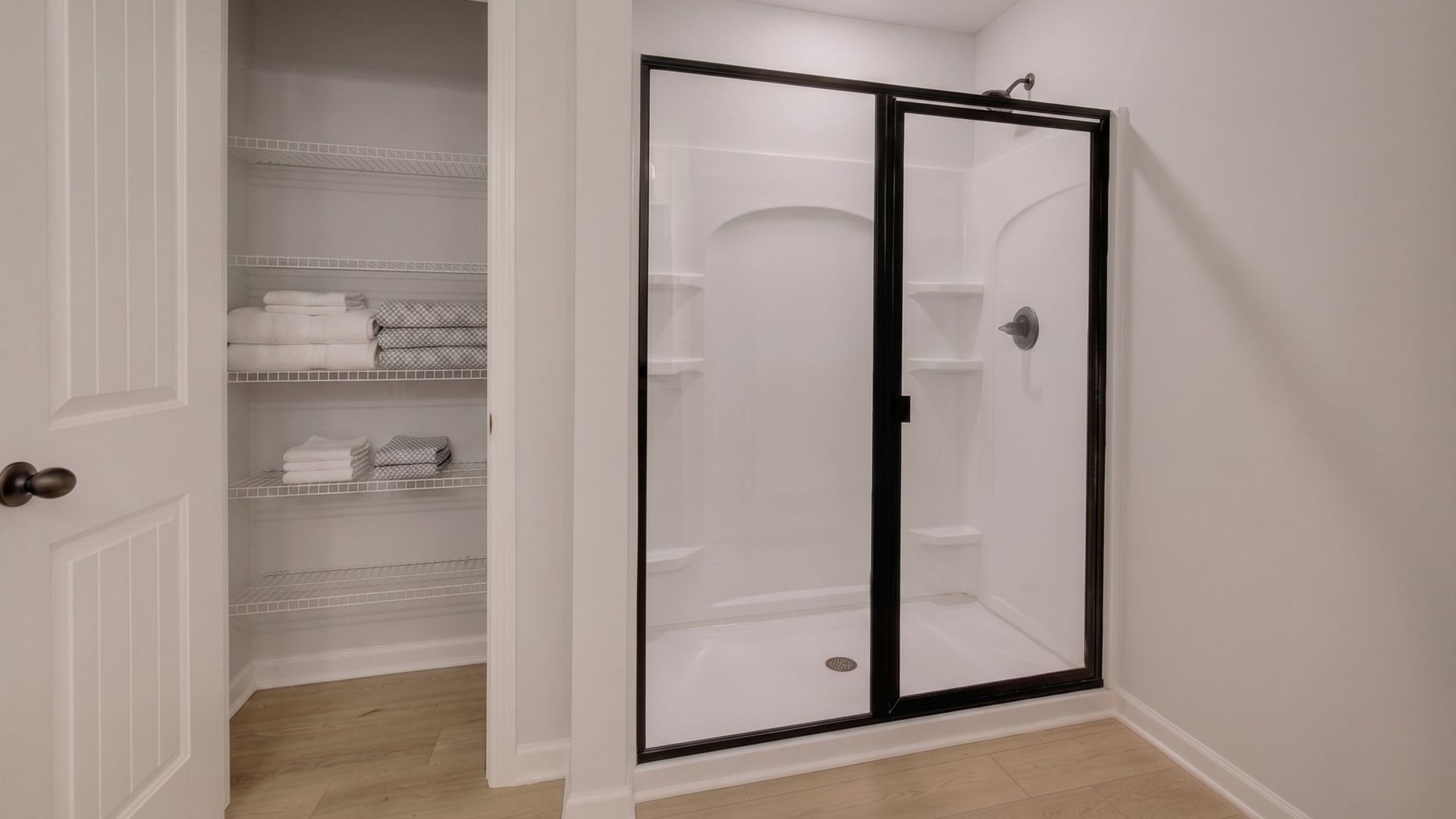 Primary bathroom with glass enclosed shower and linen closet