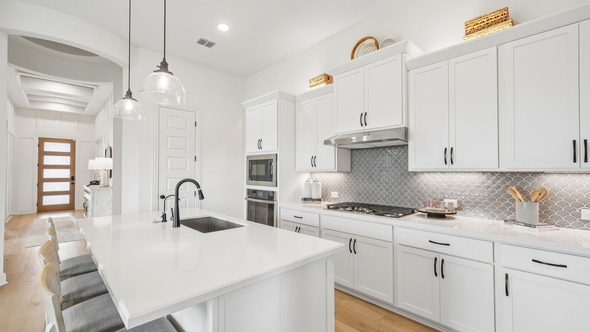Sleek kitchen design with gas cooktop, vent hood, built-in oven, and modern finishes