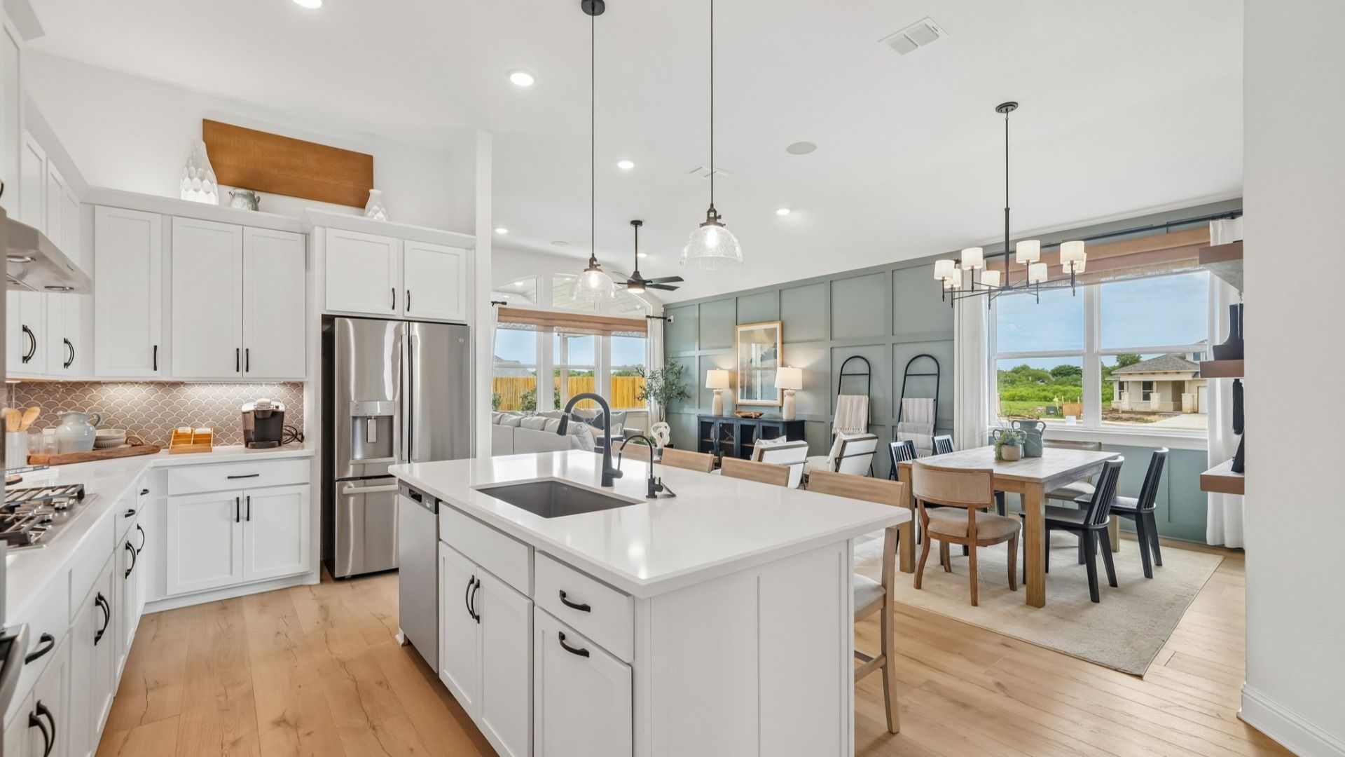 Elegant kitchen with gray scalloped backsplash, glass pendant lighting, center island, and ambient accent lighting
