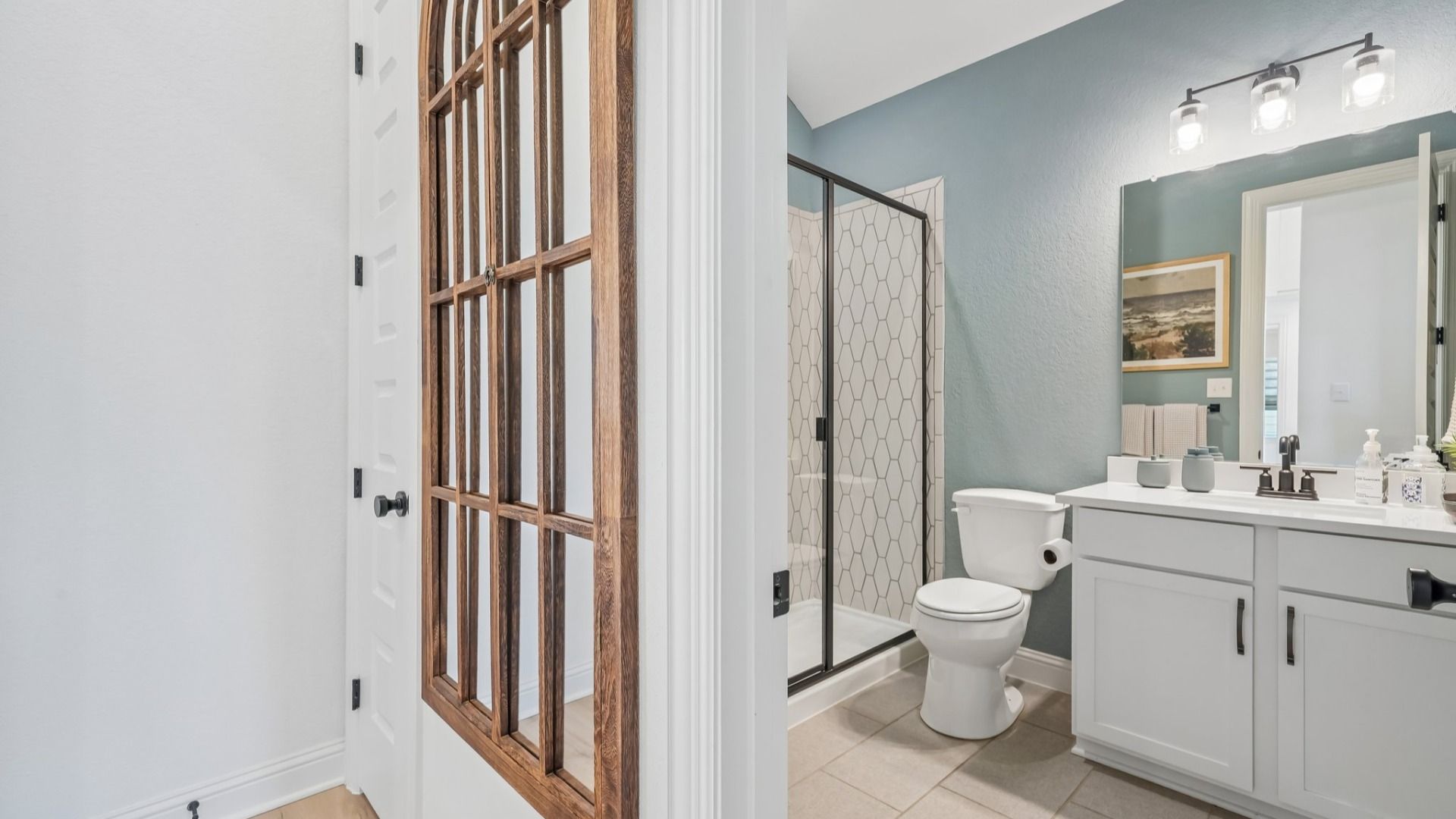 Secondary bathroom with ceramic tile shower, black framed glass door, and single vanity