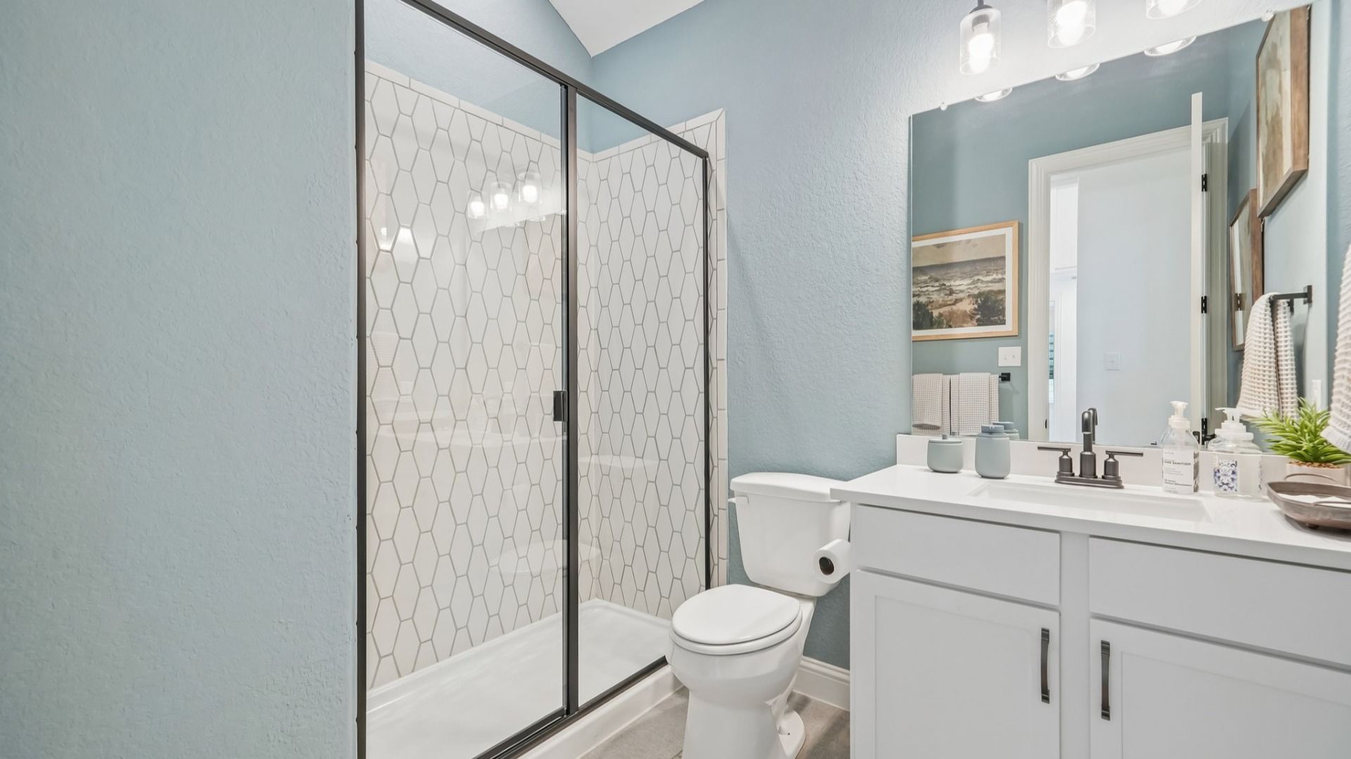 Secondary bathroom with ceramic tile shower, black framed glass door, and single vanity