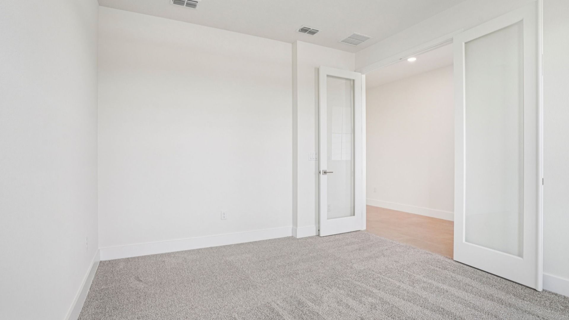 Carpeted bedroom with natural light in the Plumeria plan at Lakeside at Satilla by DRB Homes.