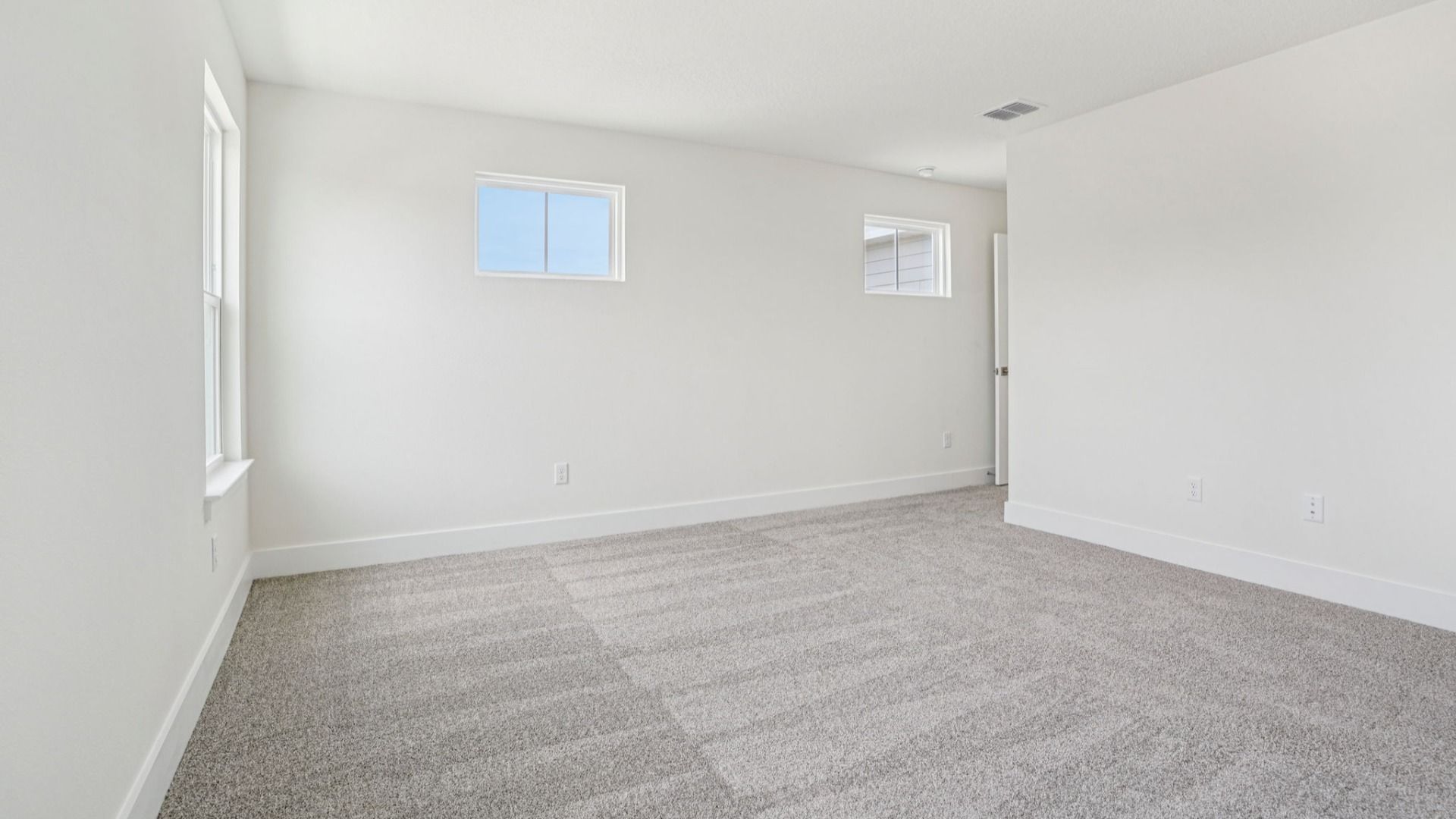 Well-lit bedroom with carpet flooring in the Plumeria plan at Lakeside at Satilla by DRB Homes.