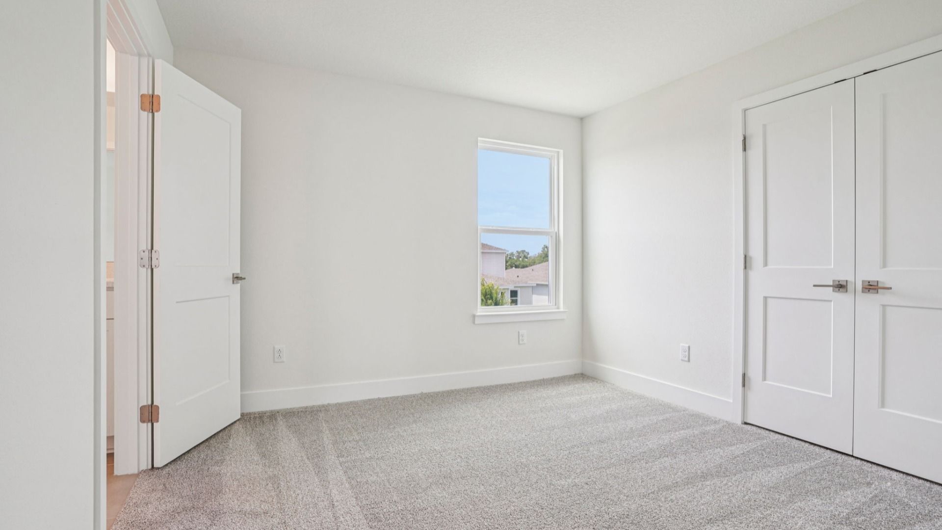 Spacious carpeted bedroom in the Plumeria plan at Lakeside at Satilla by DRB Homes.
