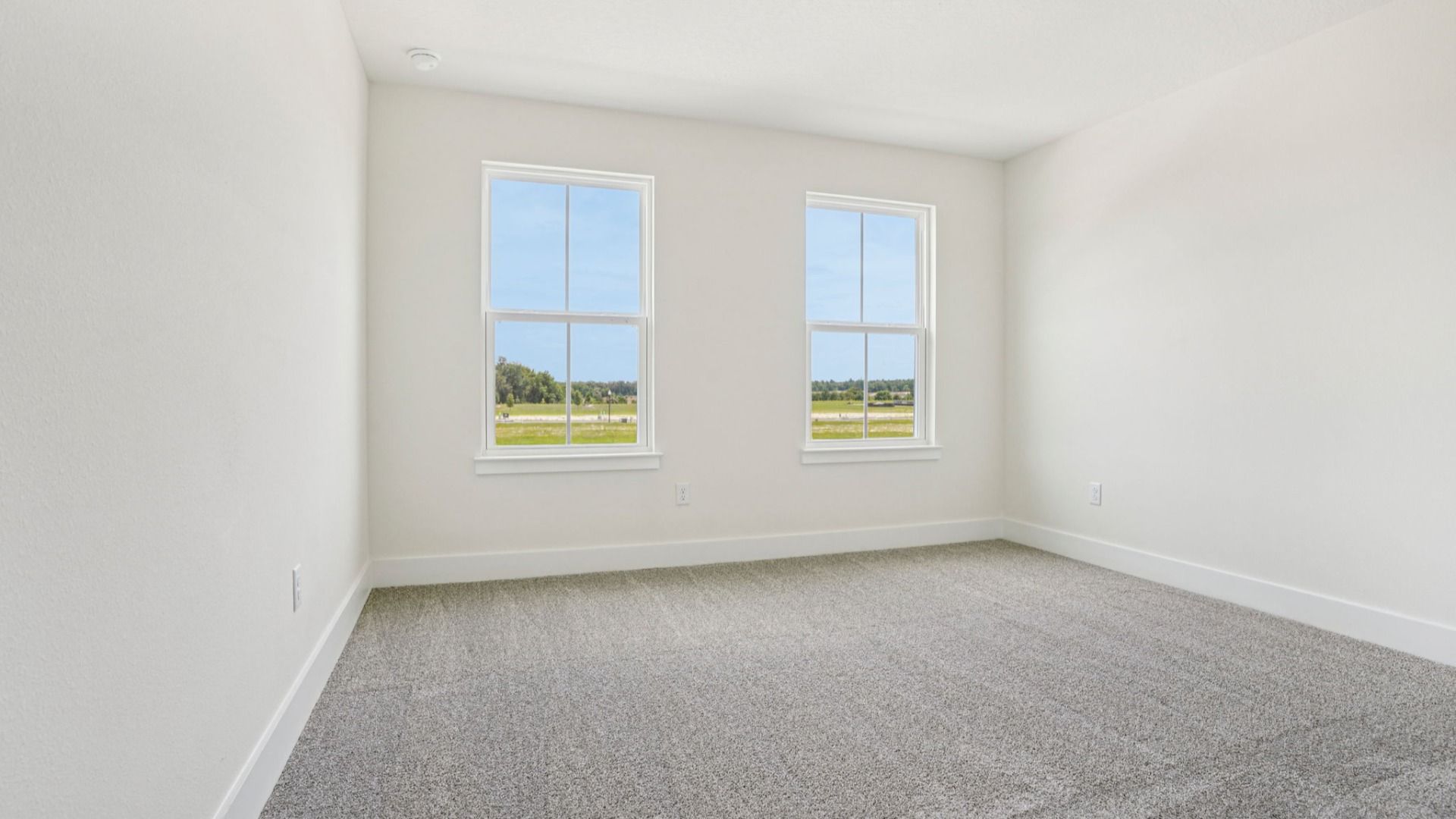 Bright bedroom with large windows in the Plumeria plan at Lakeside at Satilla by DRB Homes.